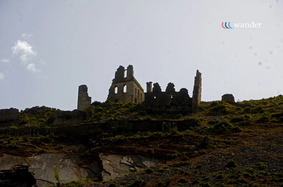 Ruins of an old stone castle on a hill with a partly cloudy sky in the background.