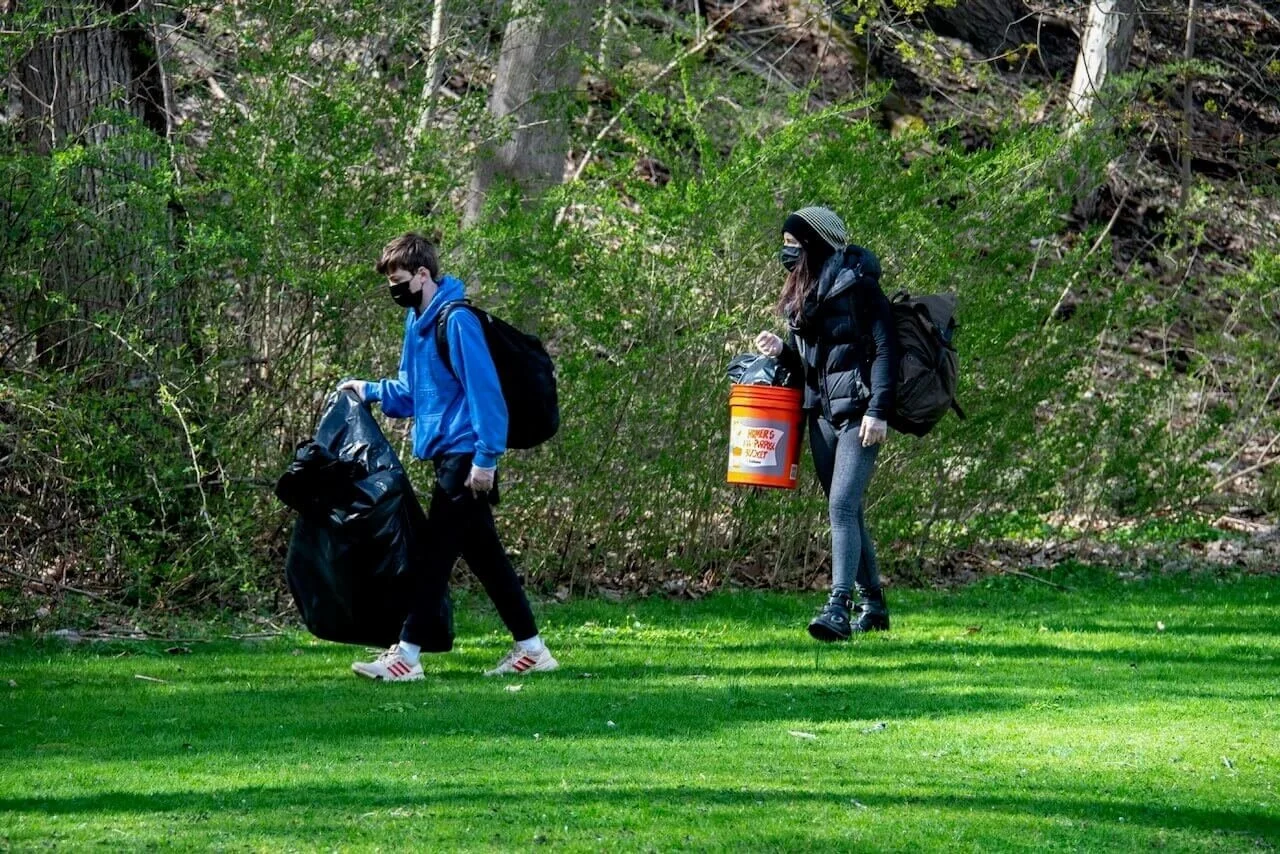 two people walking through park picking up trash