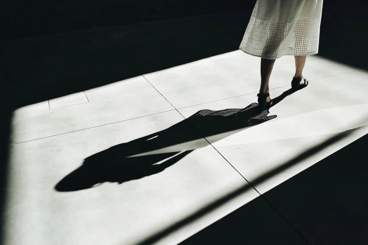 shadow on floor behind woman's feet like trauma trailing survivors