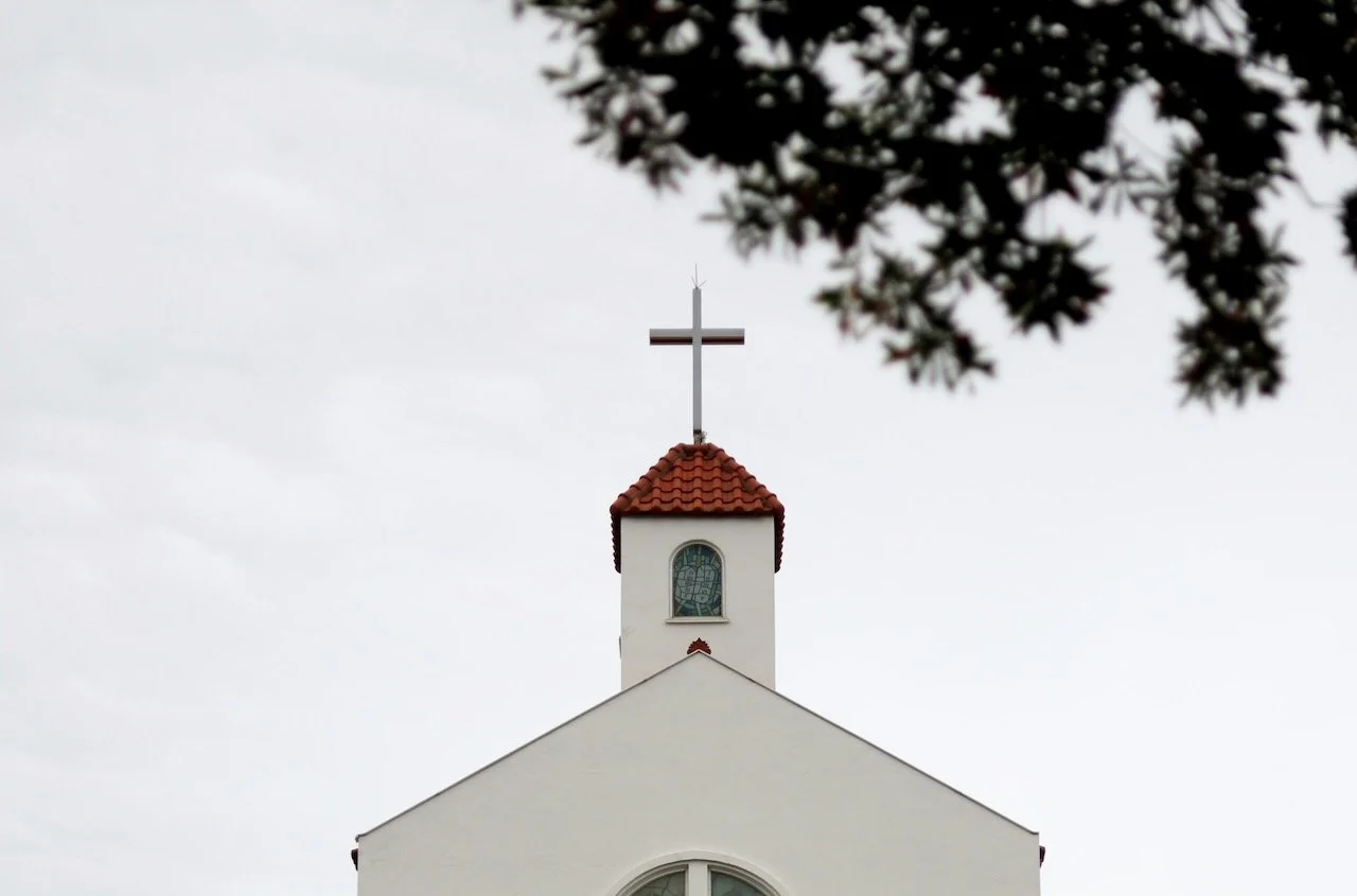 white church steeple against sky where community or religious trauma happens
