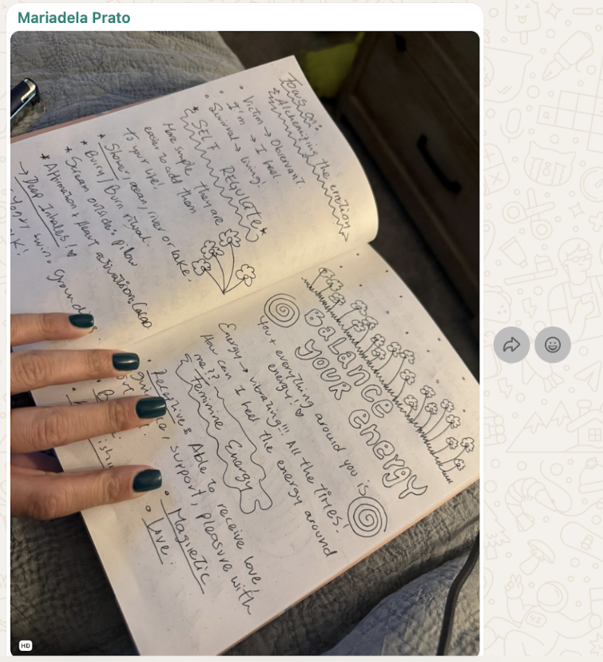 Open notebook page with handwritten notes about energy and well-being, decorated with doodles of flowers, spirals, and clouds, and a person's hand with dark green nails pointing at the page.