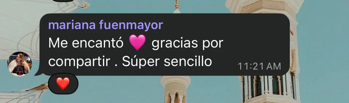 A screenshot of a message in Spanish expressing enjoyment and gratitude for sharing, with pink and red heart emojis, over a background featuring a building with white tower-like structures against a blue sky.
