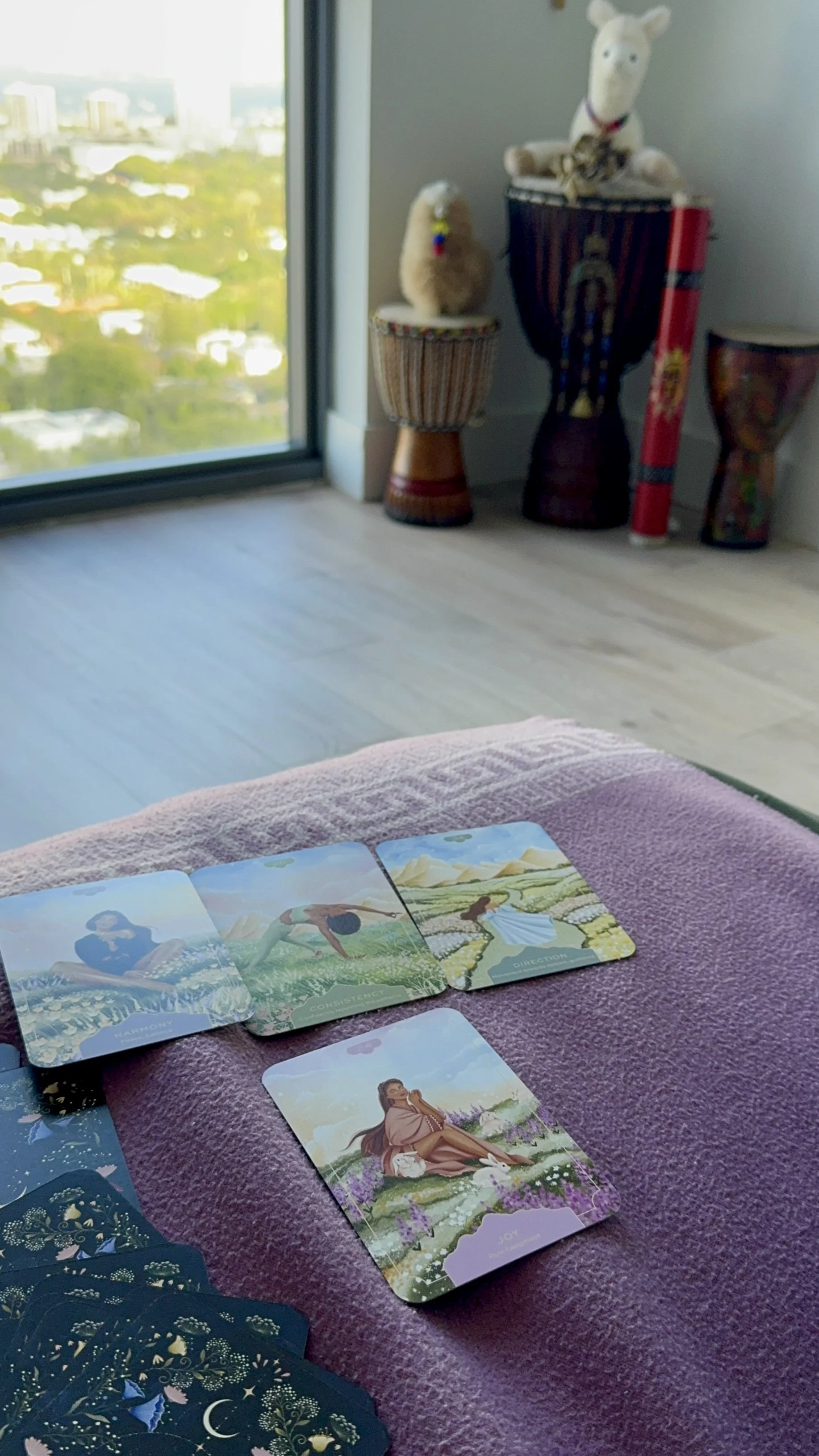 A spread of decorative cups, mugs, and papers on a table with a white patterned tablecloth, with a body of water in the background.
