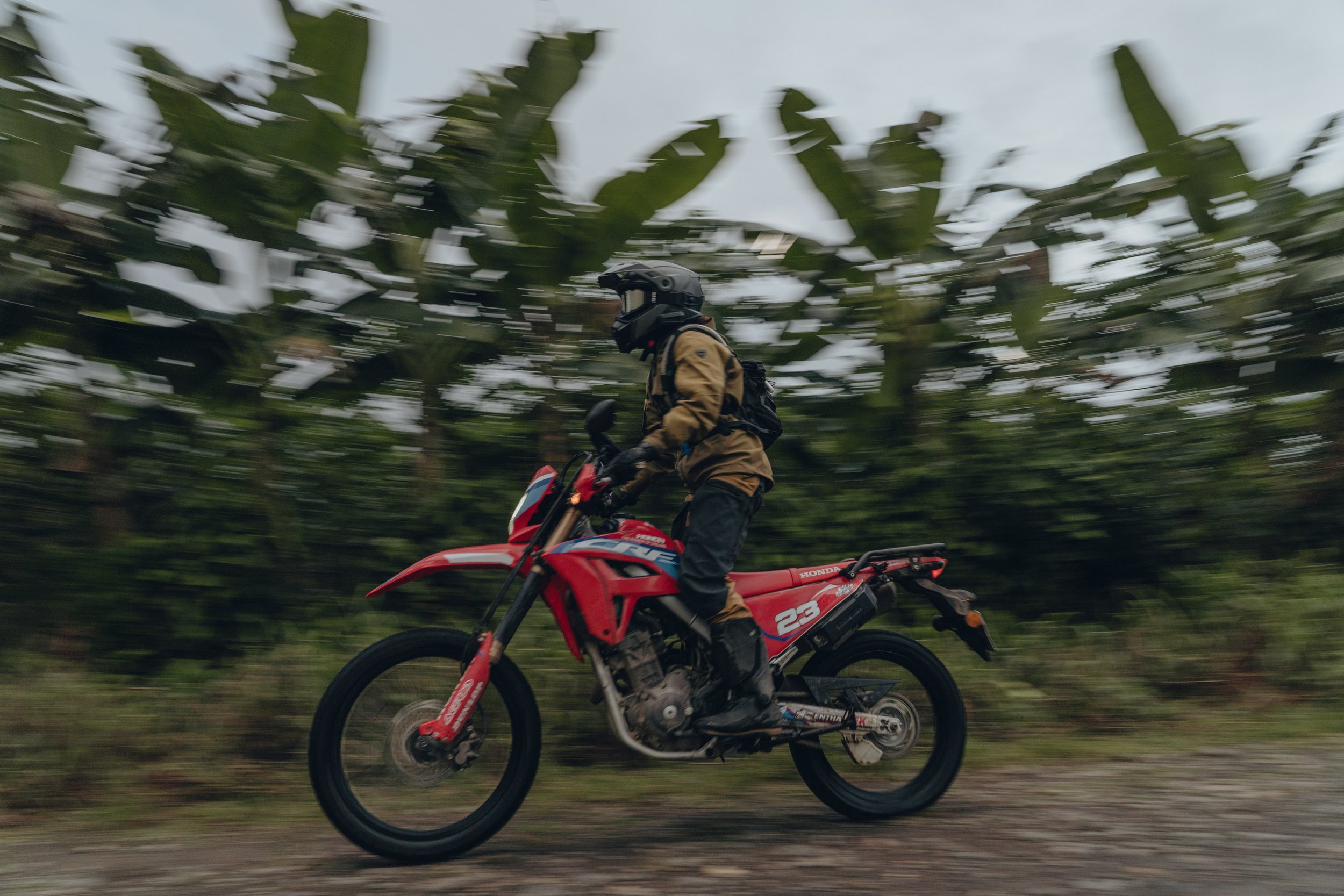 Golnoosh Namazi riding a red dirt bike along a jungle road in Costa Rica during a project with Infinite Adventures.