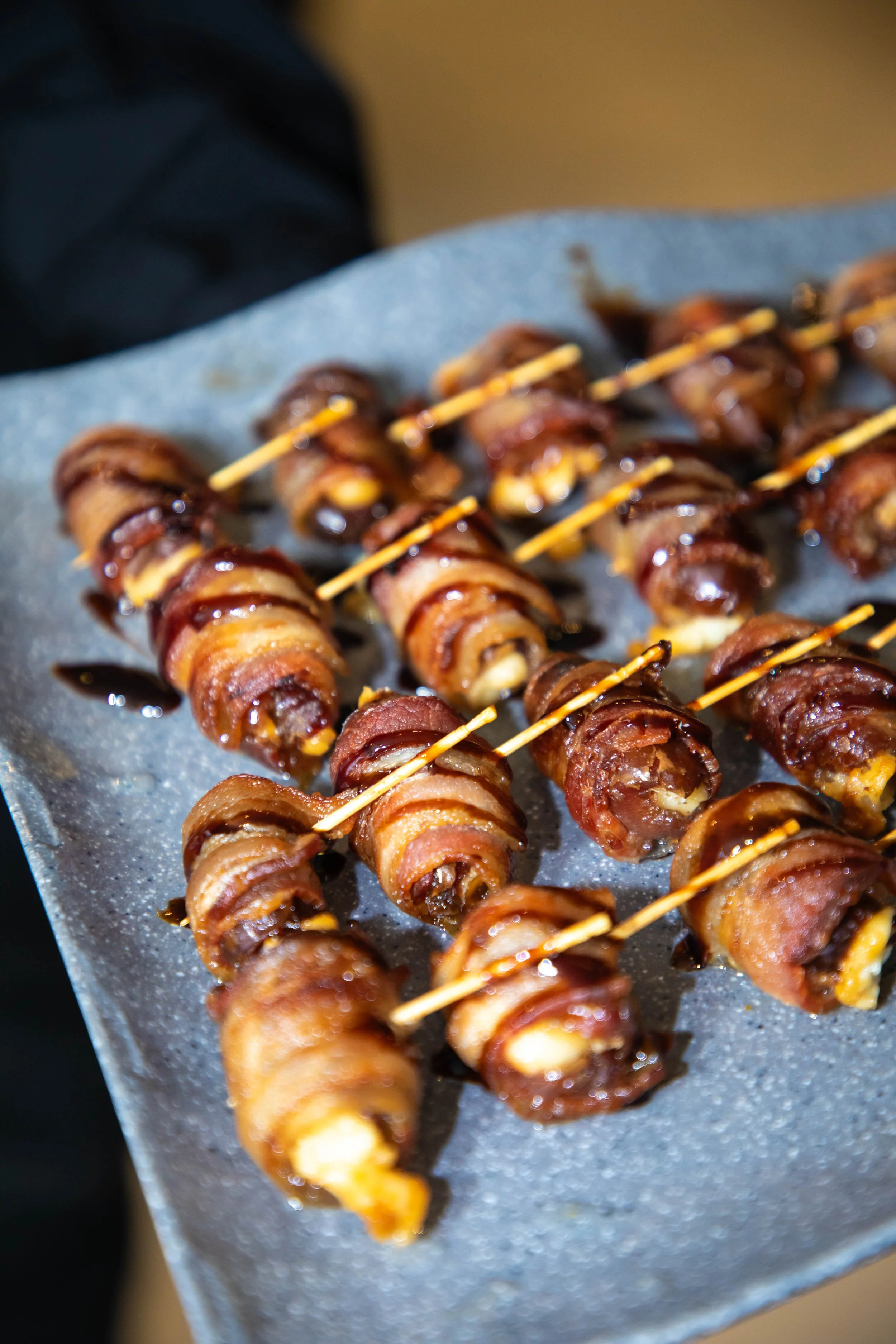 Bacon-wrapped jalapeno poppers on a tray with toothpicks.