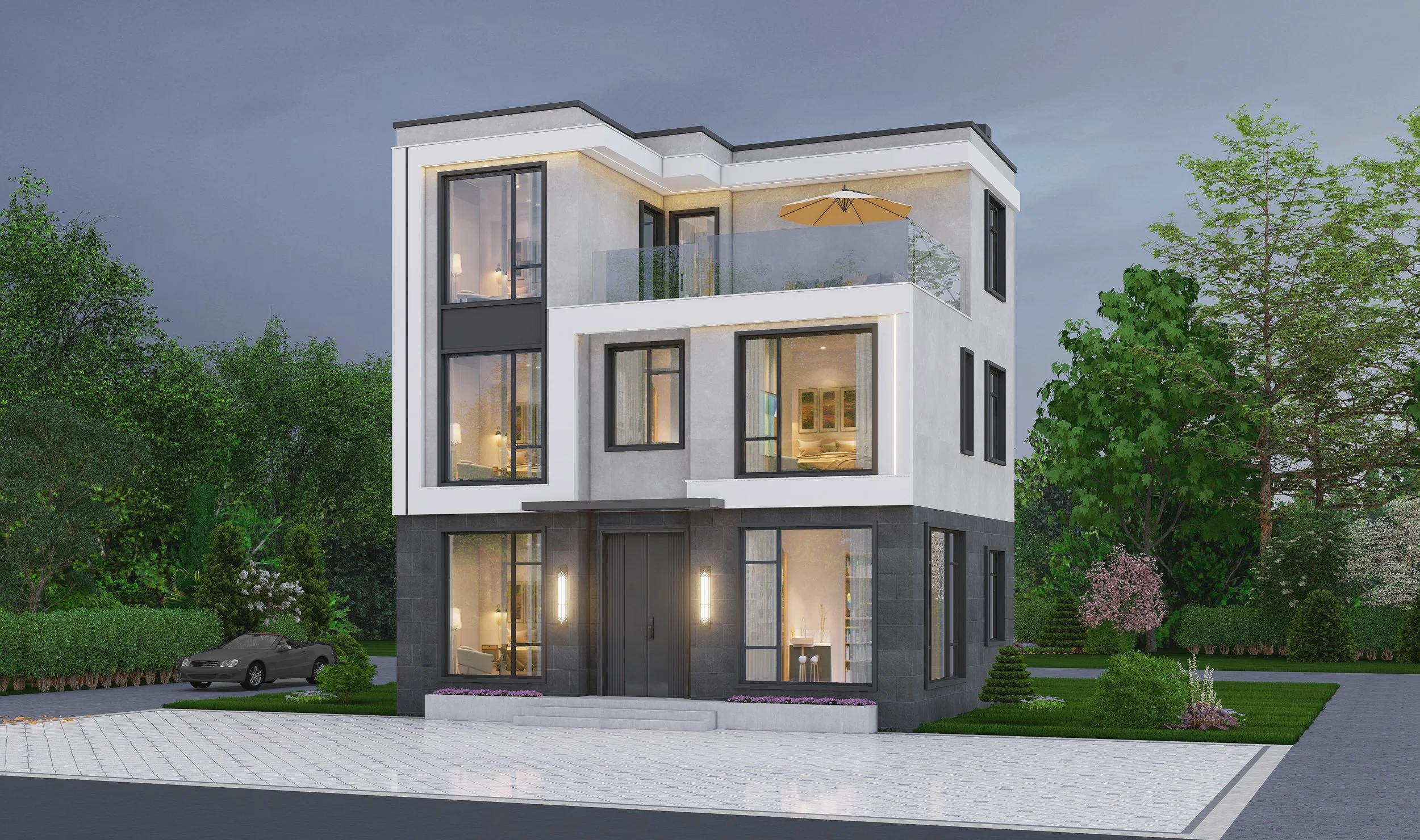Modern three-story residential building with large windows, a balcony with a glass railing, and outdoor lighting, surrounded by greenery and parking area.