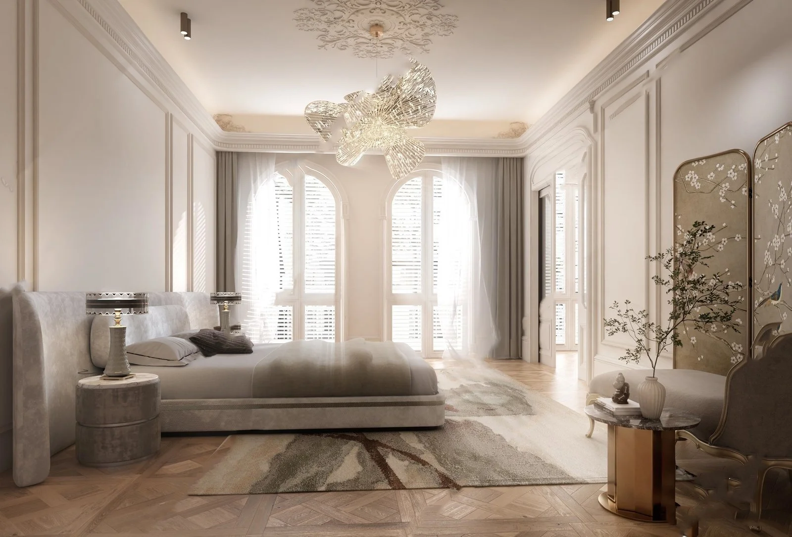 Luxurious bedroom with white walls, ornate molding, large arched windows with shutters, a modern chandelier, plush white bed with gray and black pillows, a round side table with a lamp, a vase with flowers on an elegant chair, and a decorative foldin