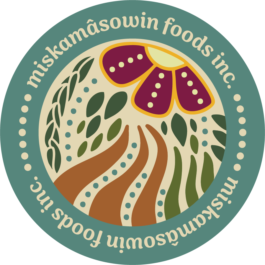 A circular logo with the text 'miskamáowin foods inc.' around the top half and bottom half. The central design features a flower with purple petals, green leaves, a stylized field or pathway in brown, and dotted patterns on a cream background.
