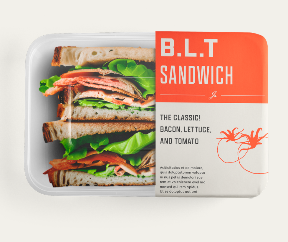 A prefixed sandwich in a clear container with lettuce, tomato, bacon, and deli meat on toasted bread, labeled as a B.L.T. sandwich with a red and white packaging design.