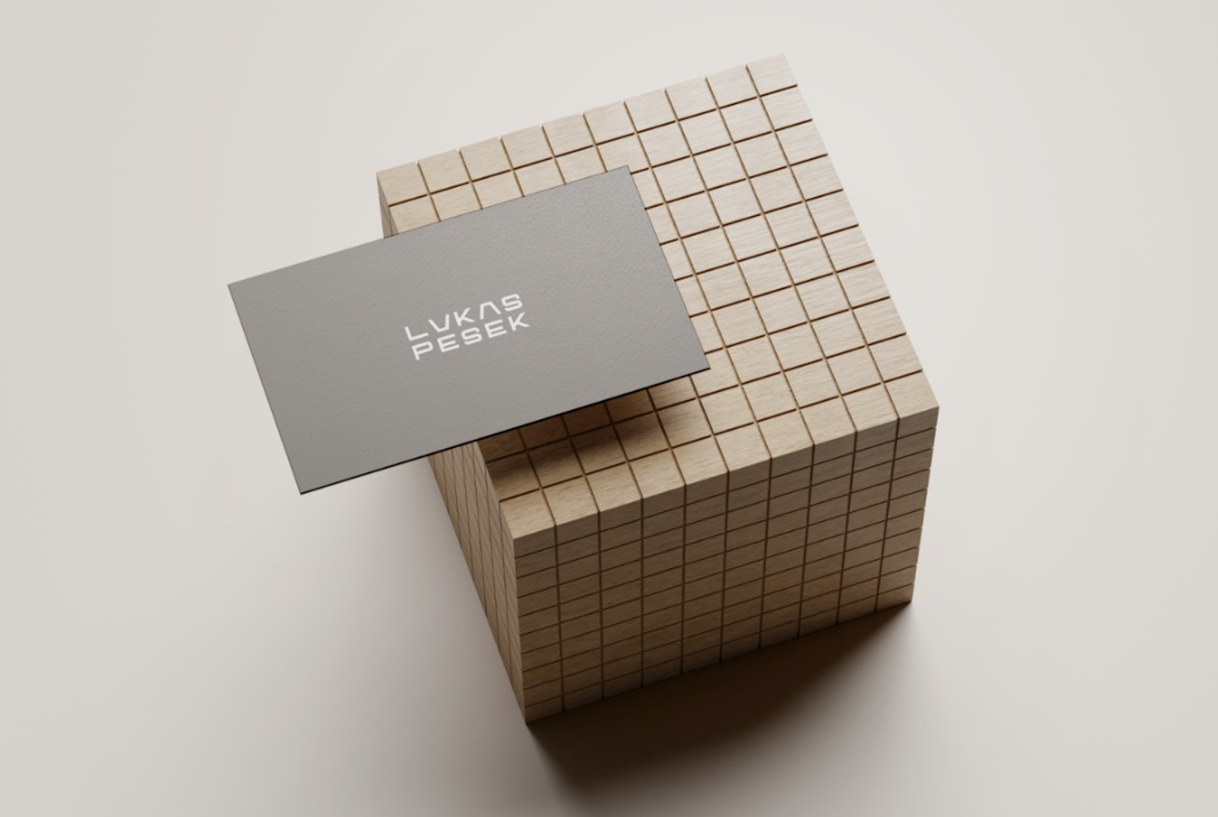 A stack of small wooden cubes with a gray business card on top. The business card has white text that reads 'Lukas PeseK.' The background is plain and light-colored. Robert Ranfranz branding and design.
