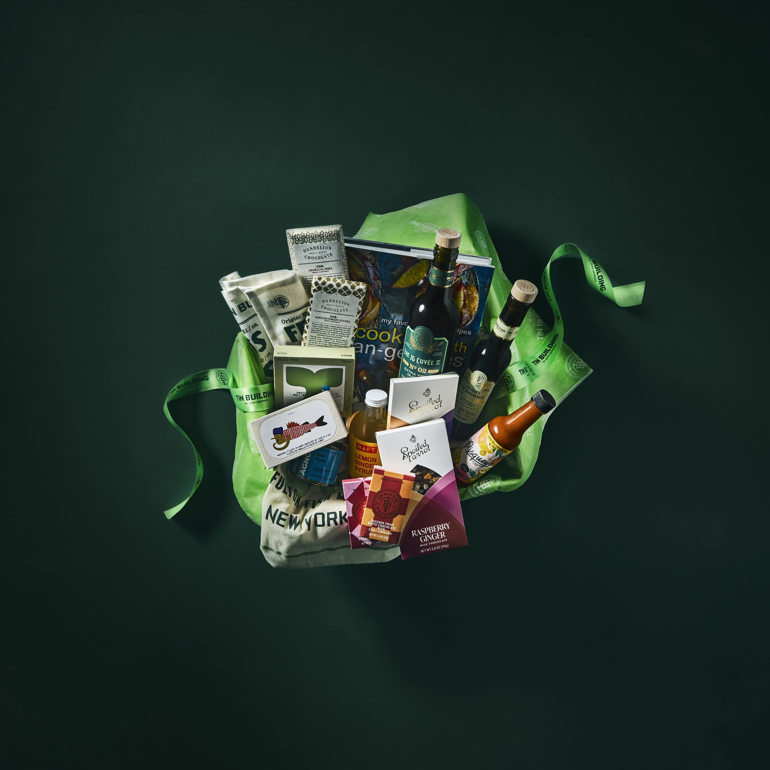A reusable tote bag filled with various food and beverage items, including bottles, snack packs, and boxes, set against a dark background.