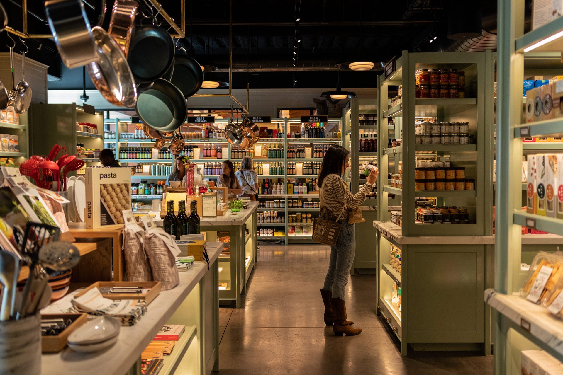 A woman shopping for products on a shelf in a grocery store.