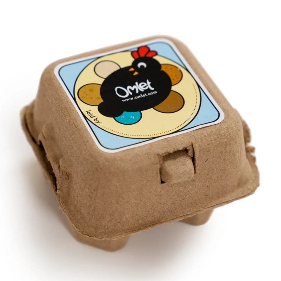 Cardboard egg carton with a colorful label featuring a cartoon chicken and eggs, with the brand name 'Omet' and a website URL.