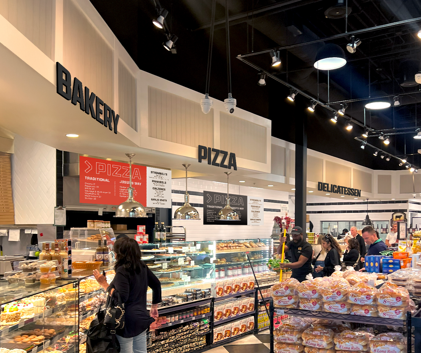Inside a bakery and deli with signs for pizza, bakery, and delicatessen; customers shopping for baked goods and sandwiches.