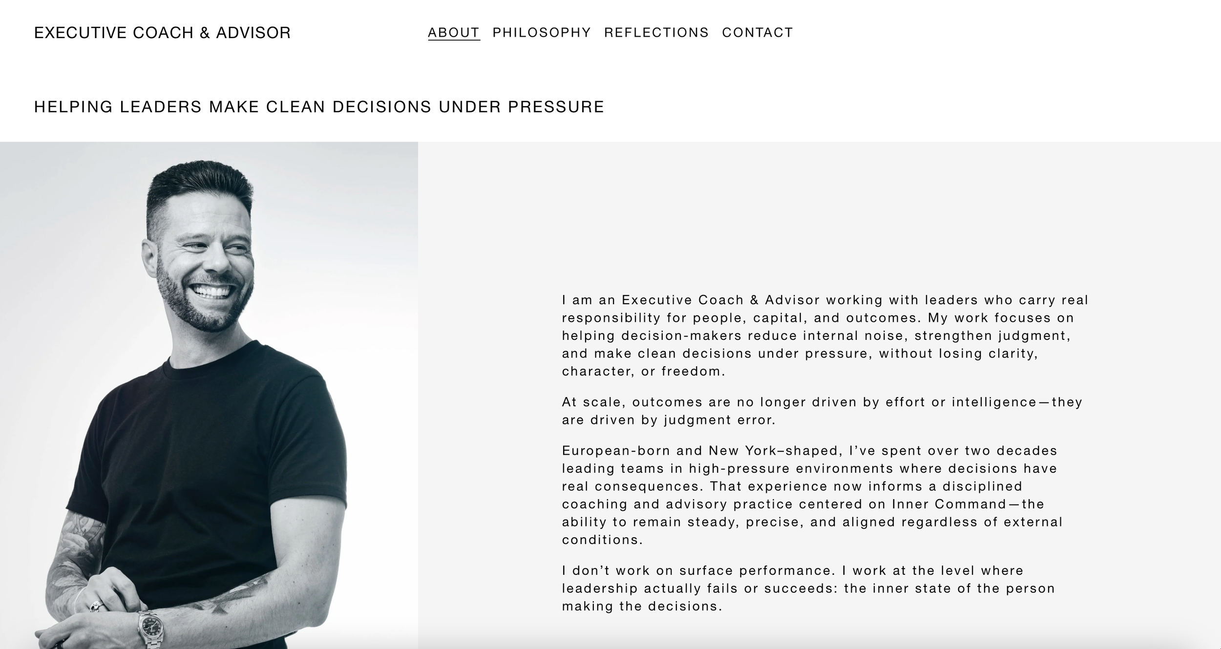 A black-and-white photograph of a smiling man with short hair and a beard, wearing a black t-shirt, standing with arms crossed. The background shows a professional website homepage for an executive coach and advisor, with navigation links and a description of his work.