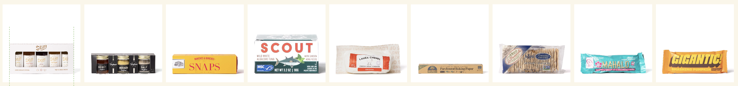 Collection of food items including a box of Sorm crackers, a set of honey, mustard, and salt jars, a box of Snap beef jerky, a Scout brand albacore tuna can, a package of Laura Chenel goat cheese, a box of parchment baking paper, a loaf of bread in plastic wrap, a package of Mahalo ginger and turmeric energy bars, and a Gigantic pumpkin seed energy bar.