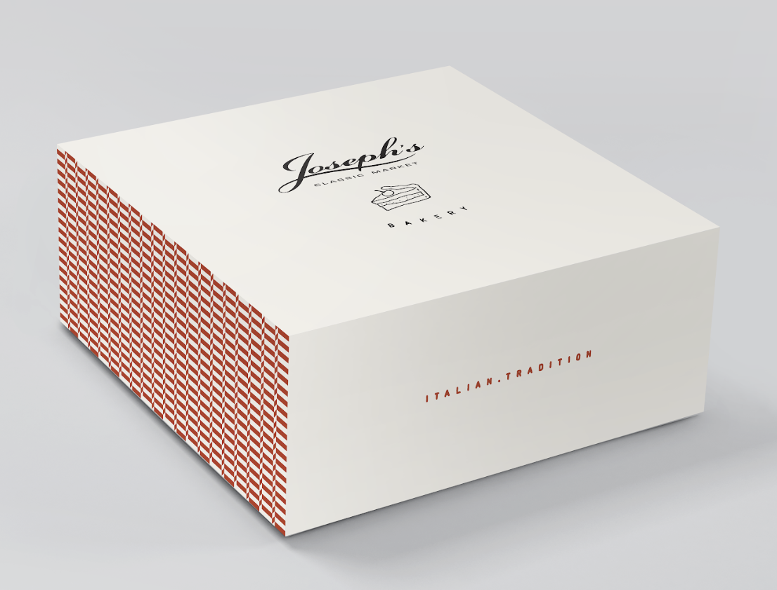 A white bakery box with red patterned sides, labeled 'Joseph's Classic Market Bakery,' and the words 'Italian Tradition' on the side.
