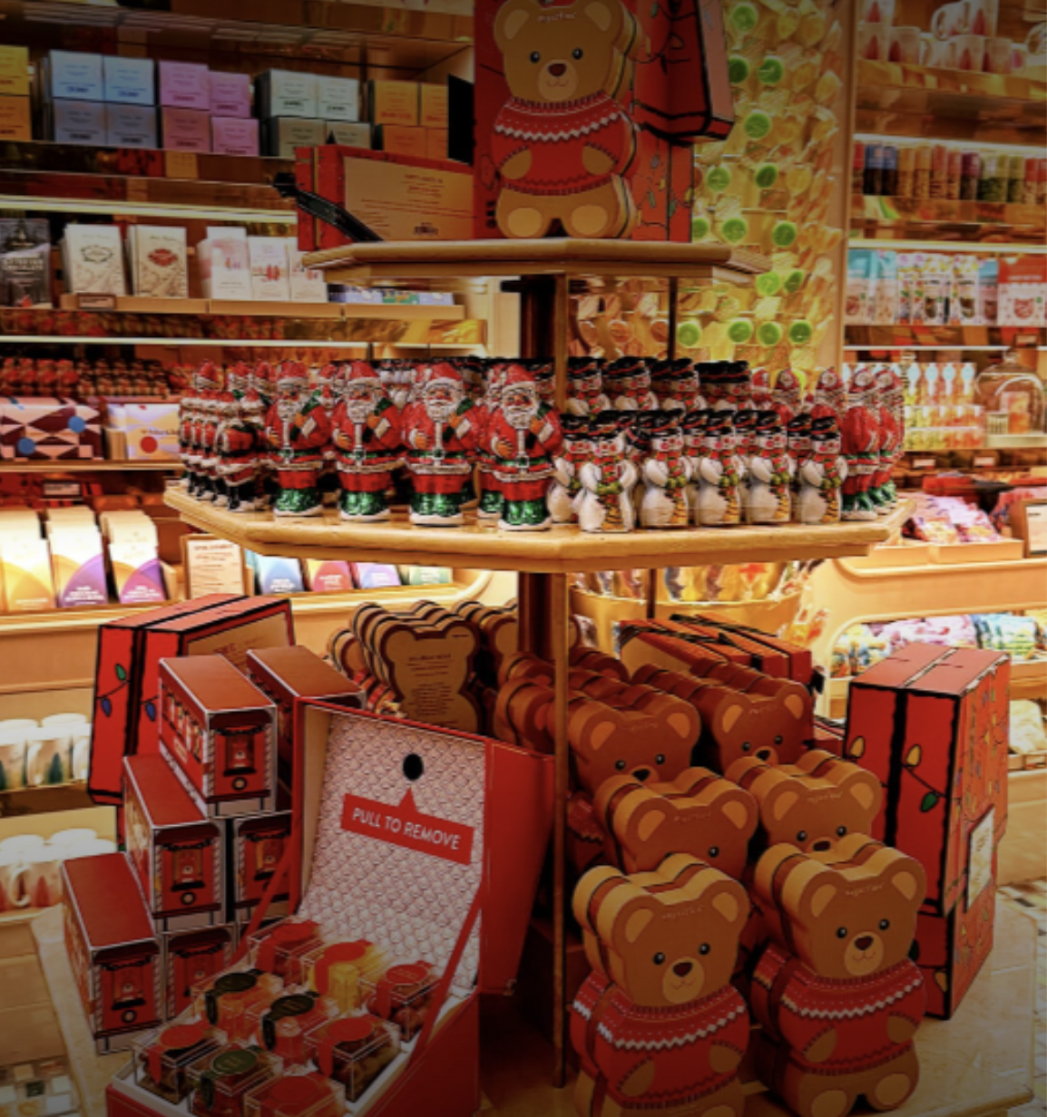 Christmas-themed plush bear and Santa figurines in a retail store display.
