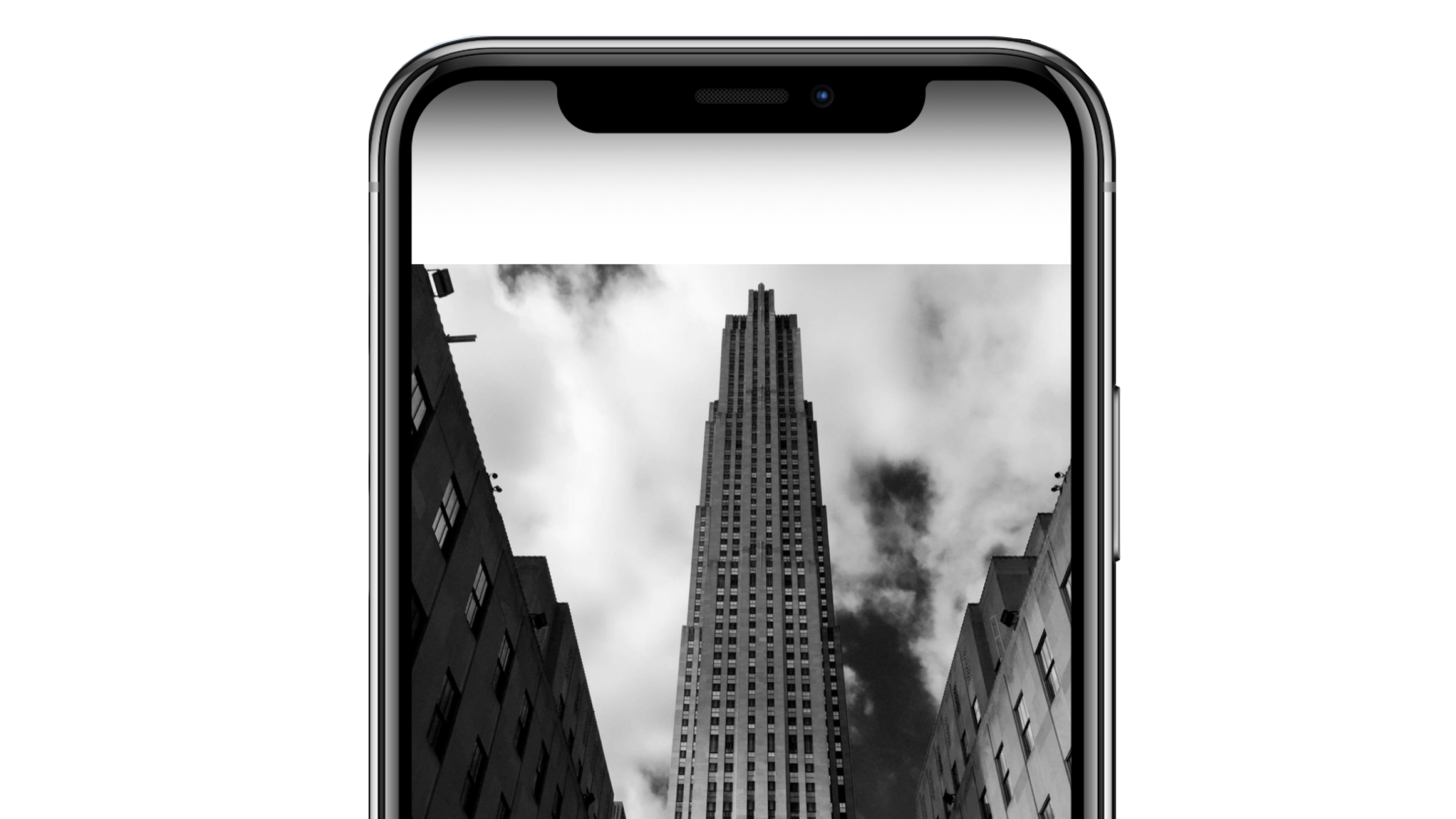 A black and white photo of the Empire State Building as seen through a smartphone screen, surrounded by buildings on either side, with cloudy sky in the background. Robert Ranfranz creative studio.