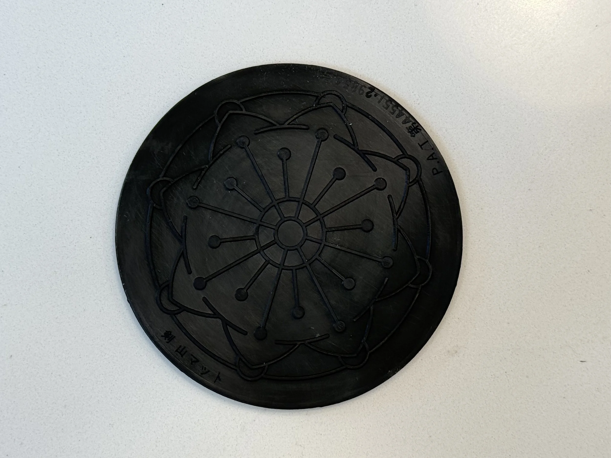 Two black circular objects with geometric patterns, partially overlapping, placed on a white surface.