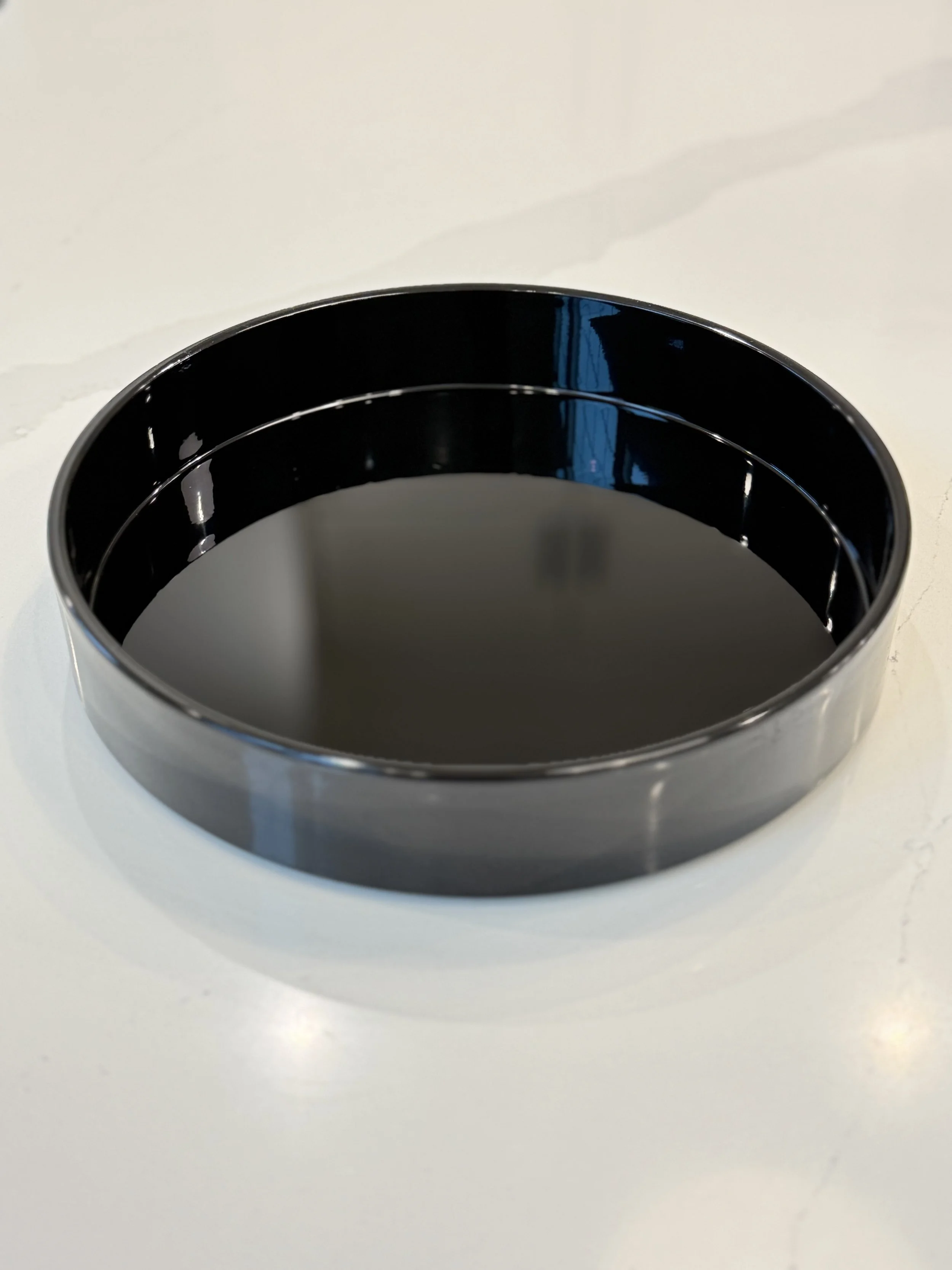 Black cylindrical object with reflective surface on a white surface