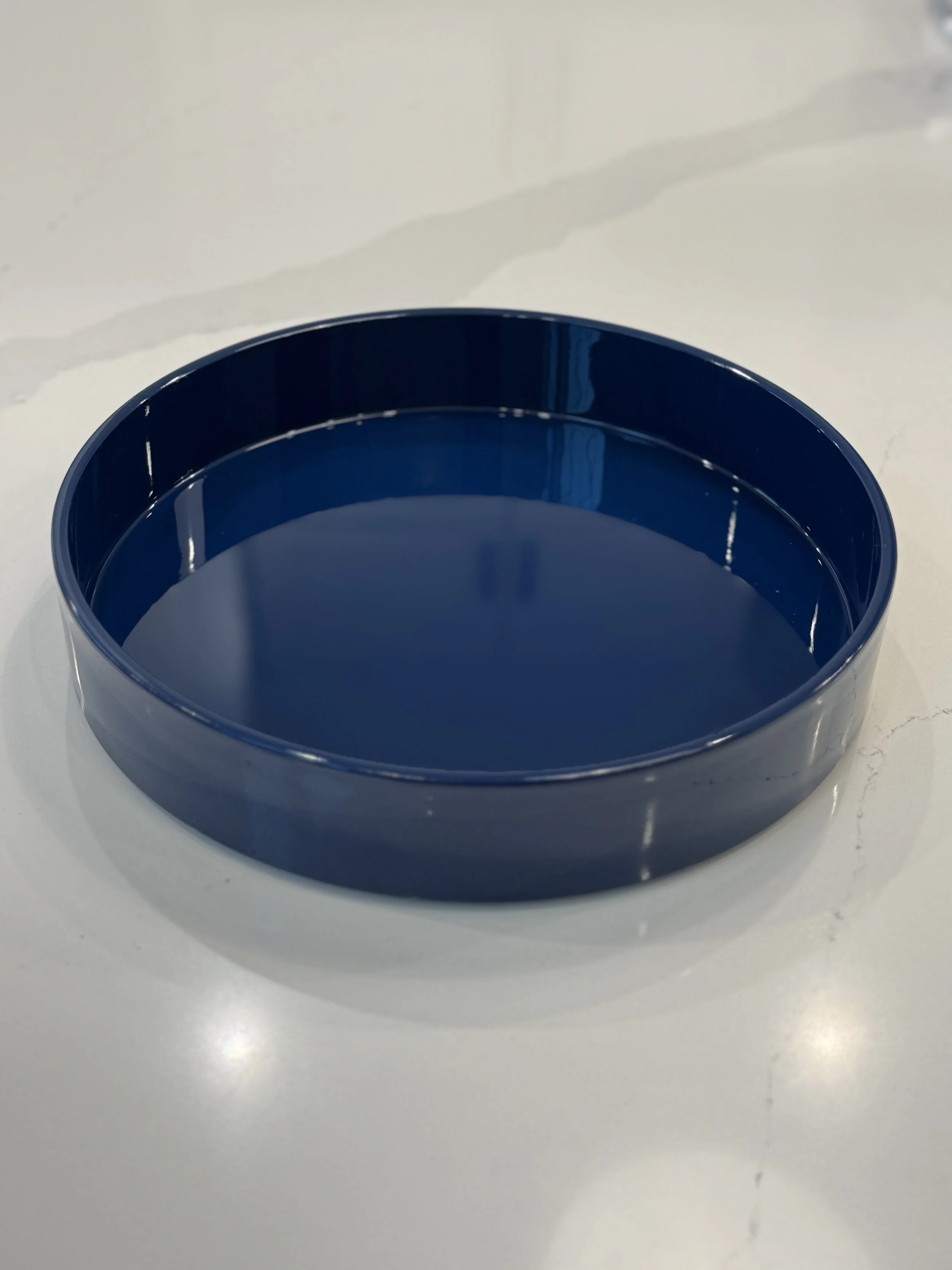 A blue circular bowl filled with water, placed on a white surface with a marble pattern.