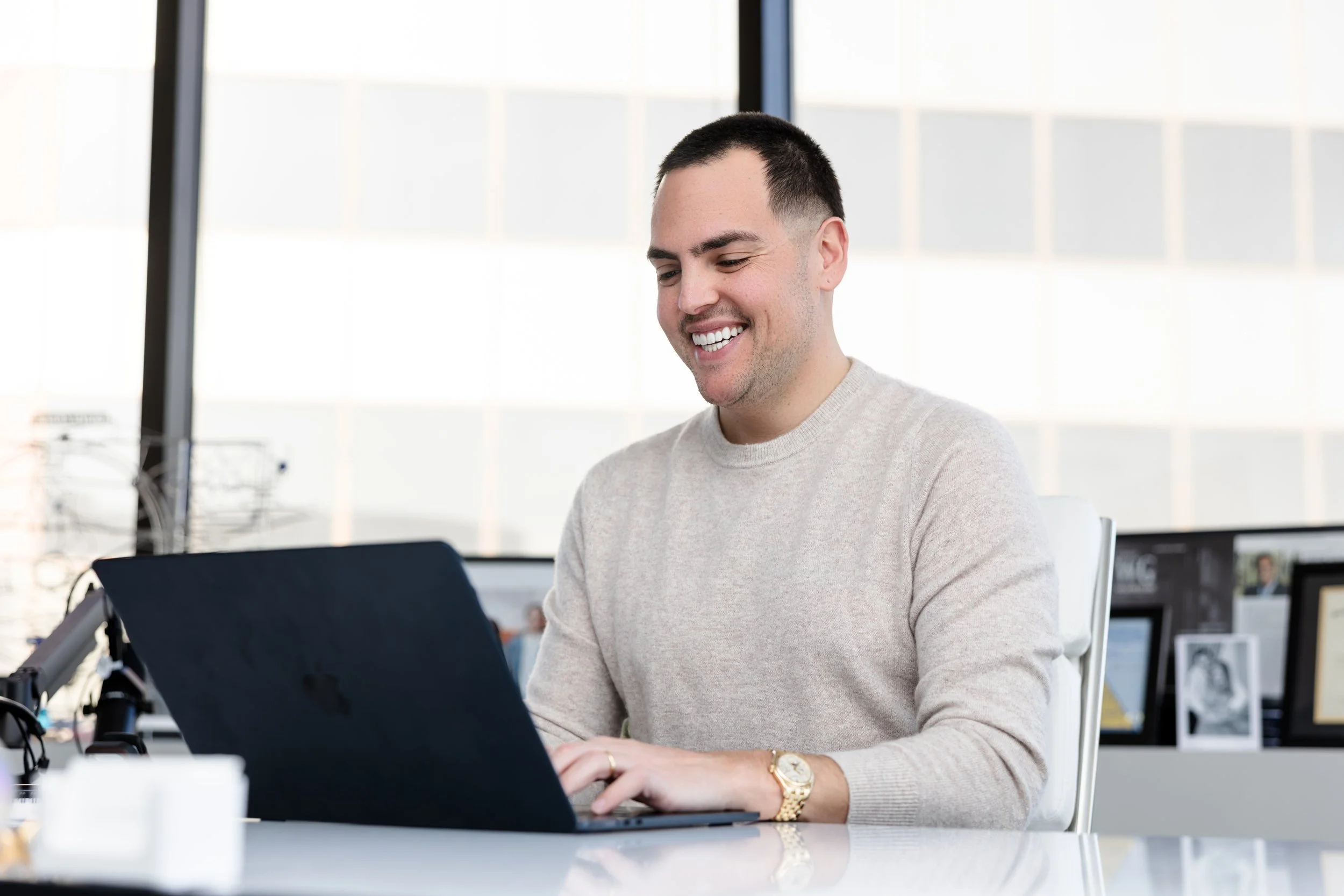 Man working on a laptop at a desk in a bright office space.
