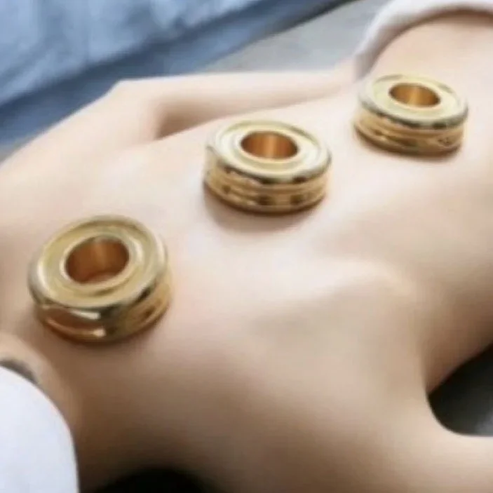 Therapeutic or massage device with three circular metal components placed on a light-colored surface