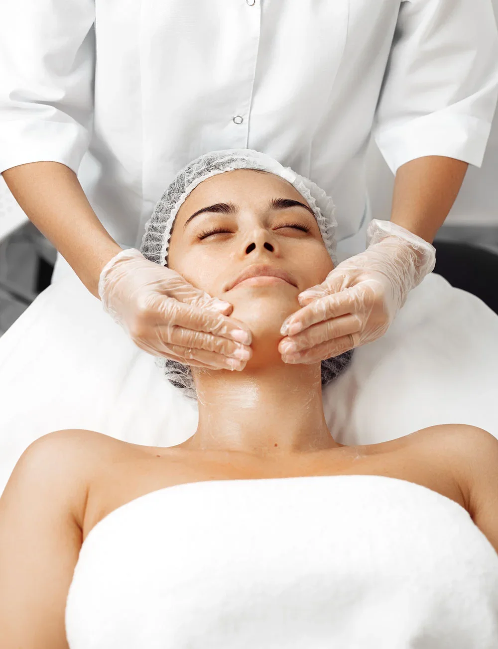 A woman receiving a facial treatment from a professional in a clinical setting.