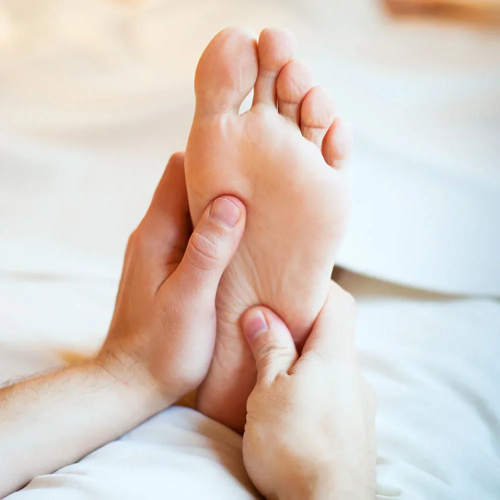 Person giving a foot massage, holding the sole and toes of one foot with both hands.
