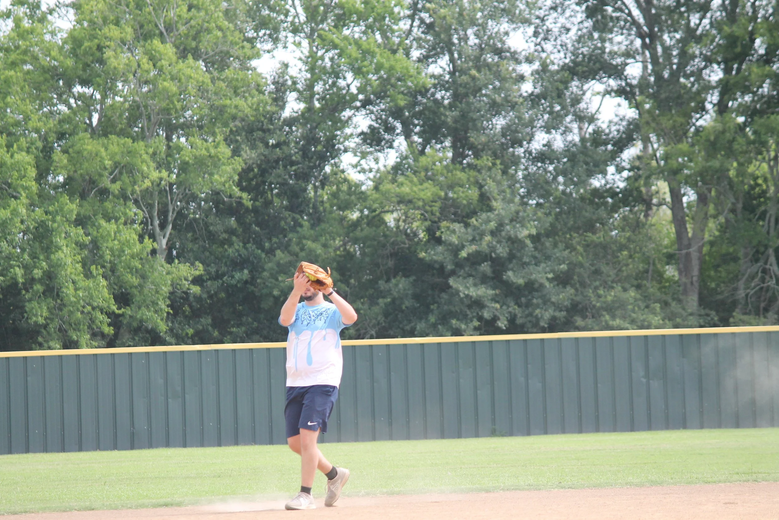 A person in athletic clothing on a baseball field catching a ball with a glove.