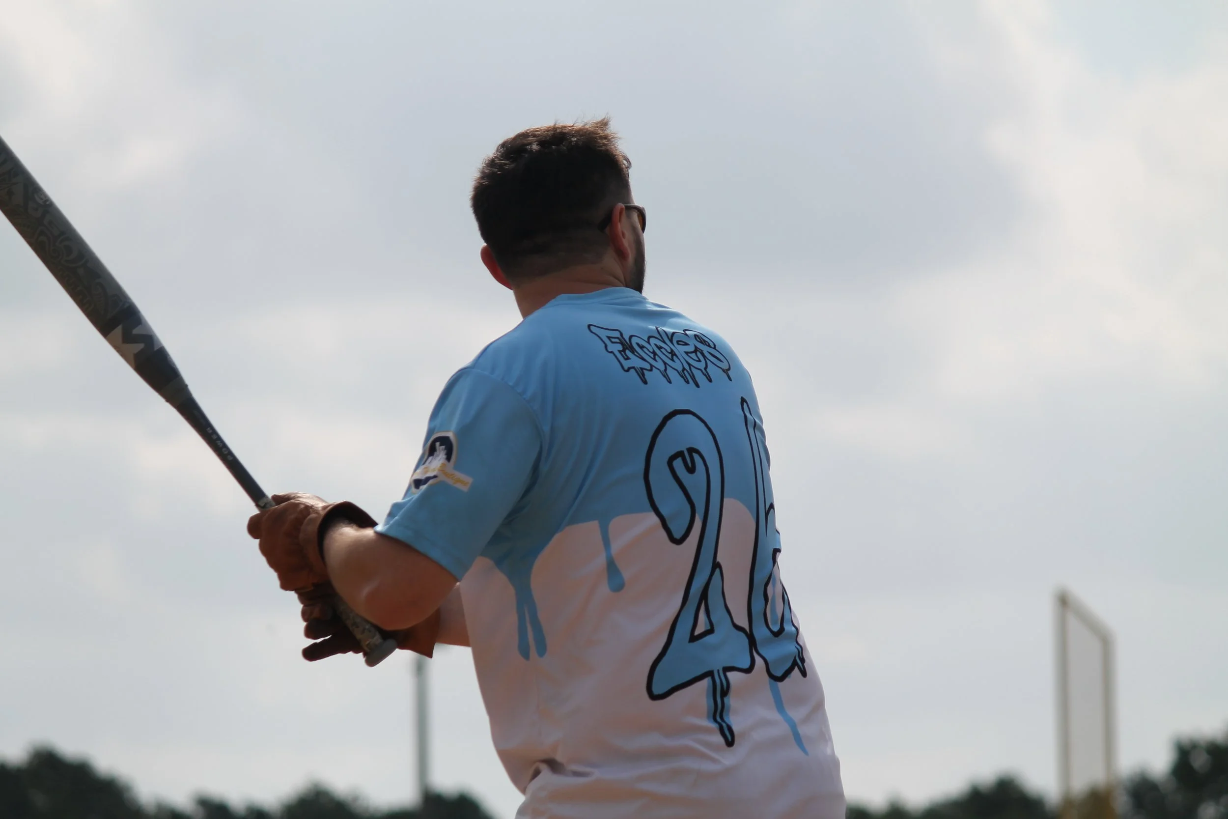 A baseball player standing on a field, holding a bat, wearing a blue and white jersey with the number 40 on the back, and looking away from the camera.