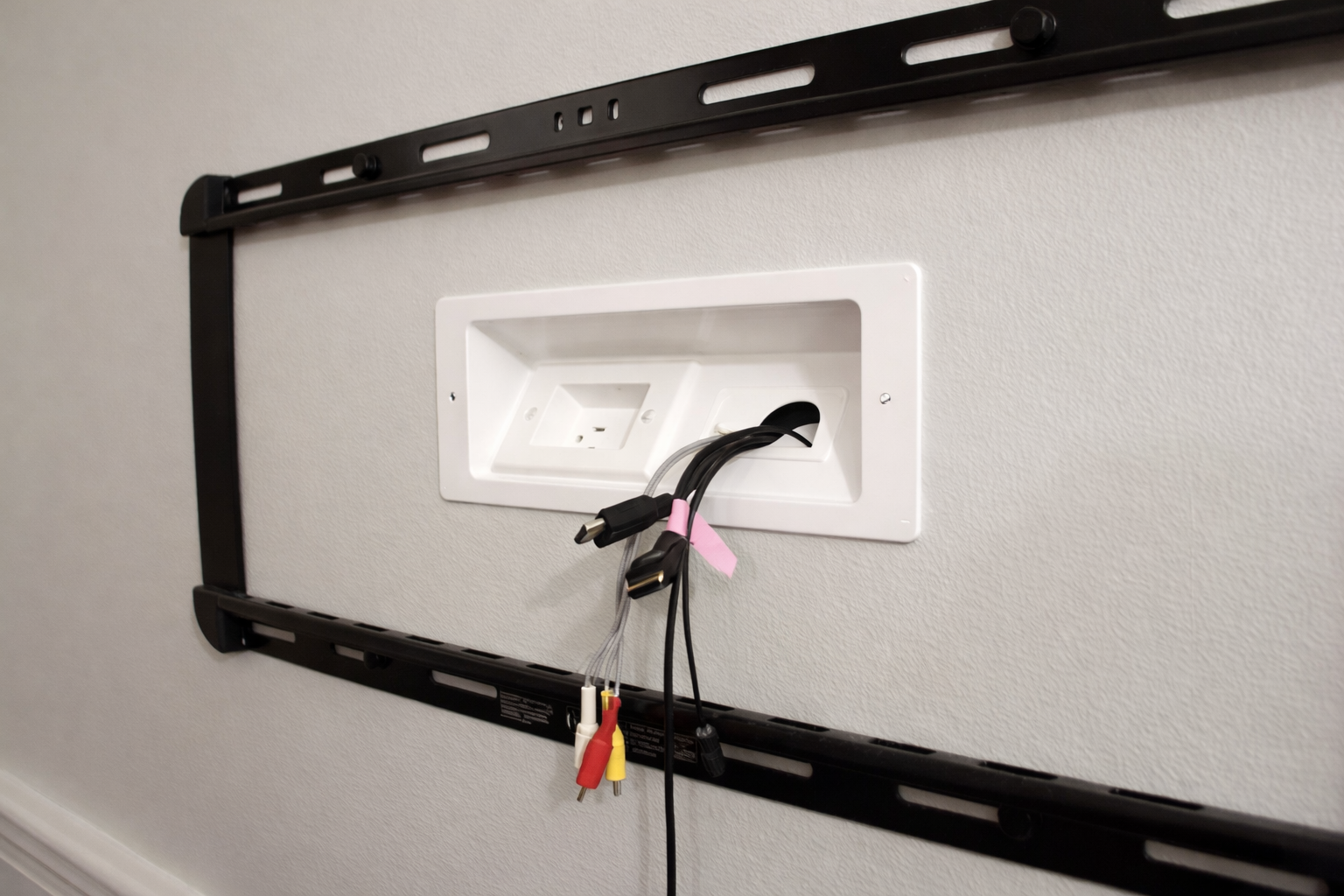 Wall-mounted TV bracket with disconnected AV cables hanging from an empty wall outlet.