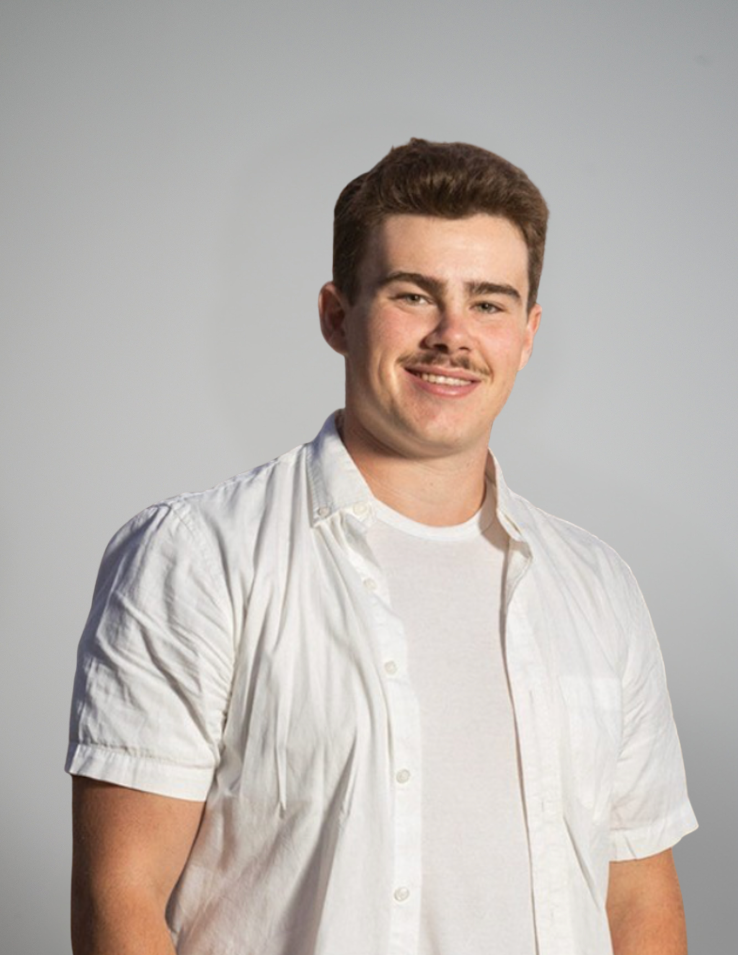 Close-up of a young man with brown hair, wearing a light-colored, short-sleeved button-up shirt, smiling against a plain gray background.