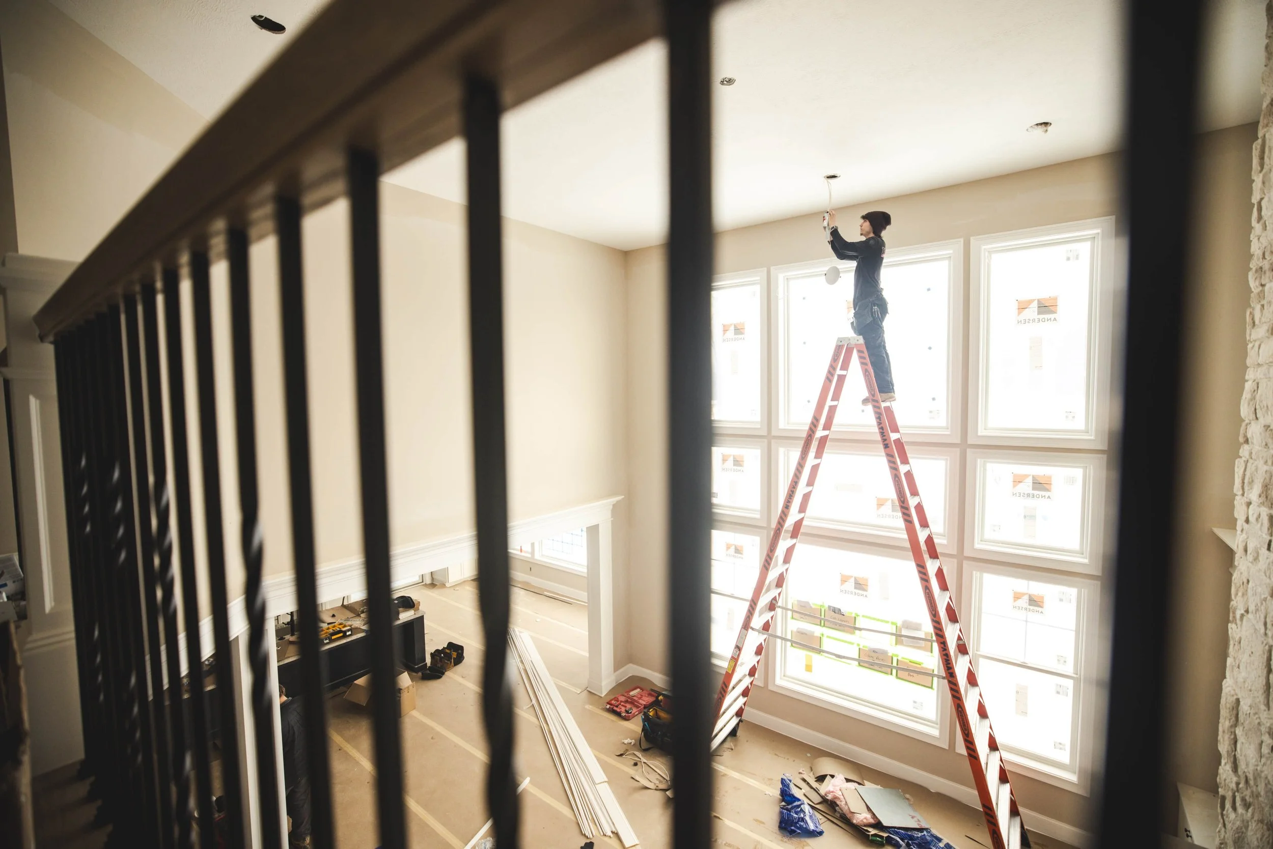 Tatman Electric electrician on ladder installing ceiling light fixture in high-end residential home Pittsburgh PA