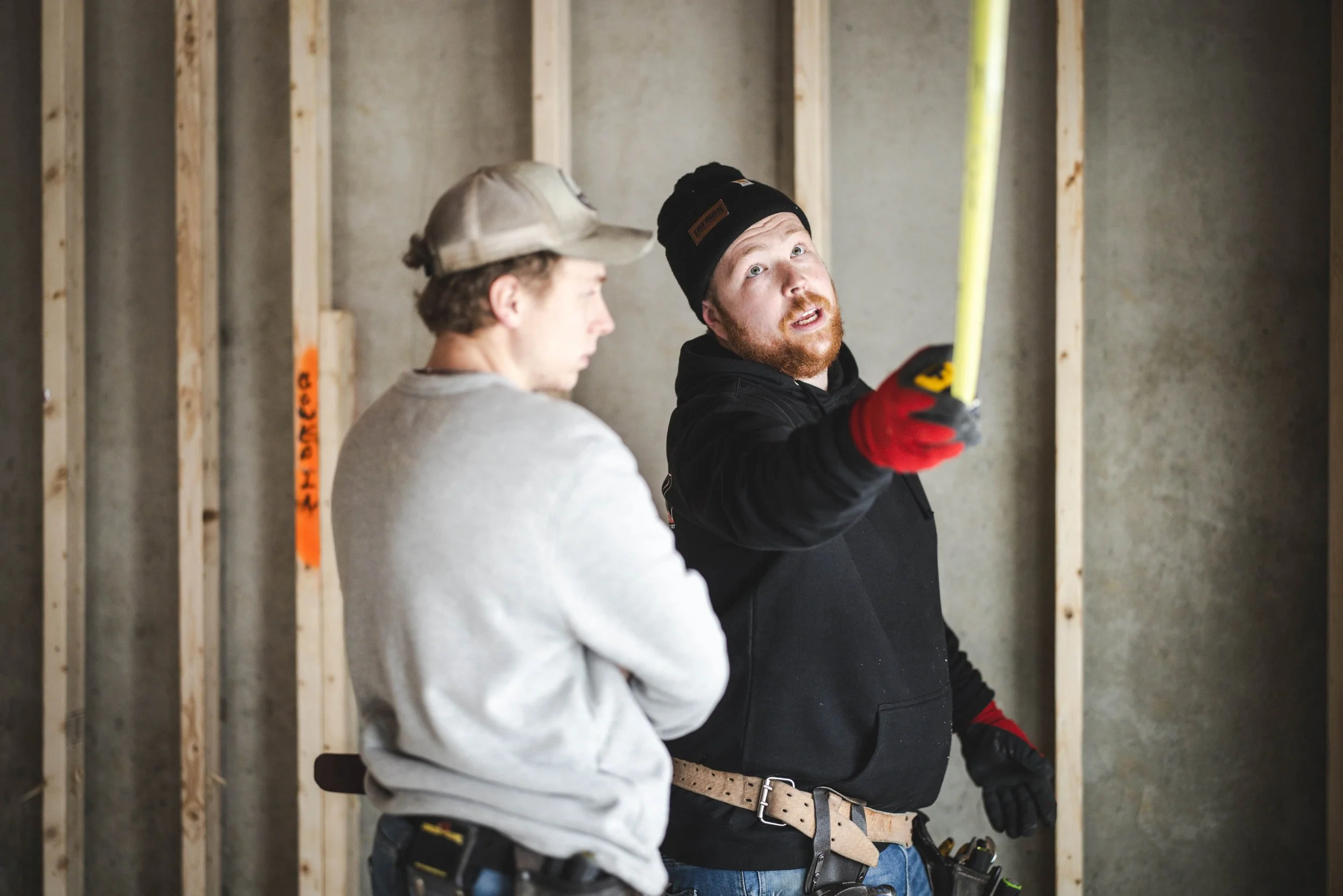 Tatman Electric electricians measuring and planning electrical work inside new construction framing Pittsburgh PA