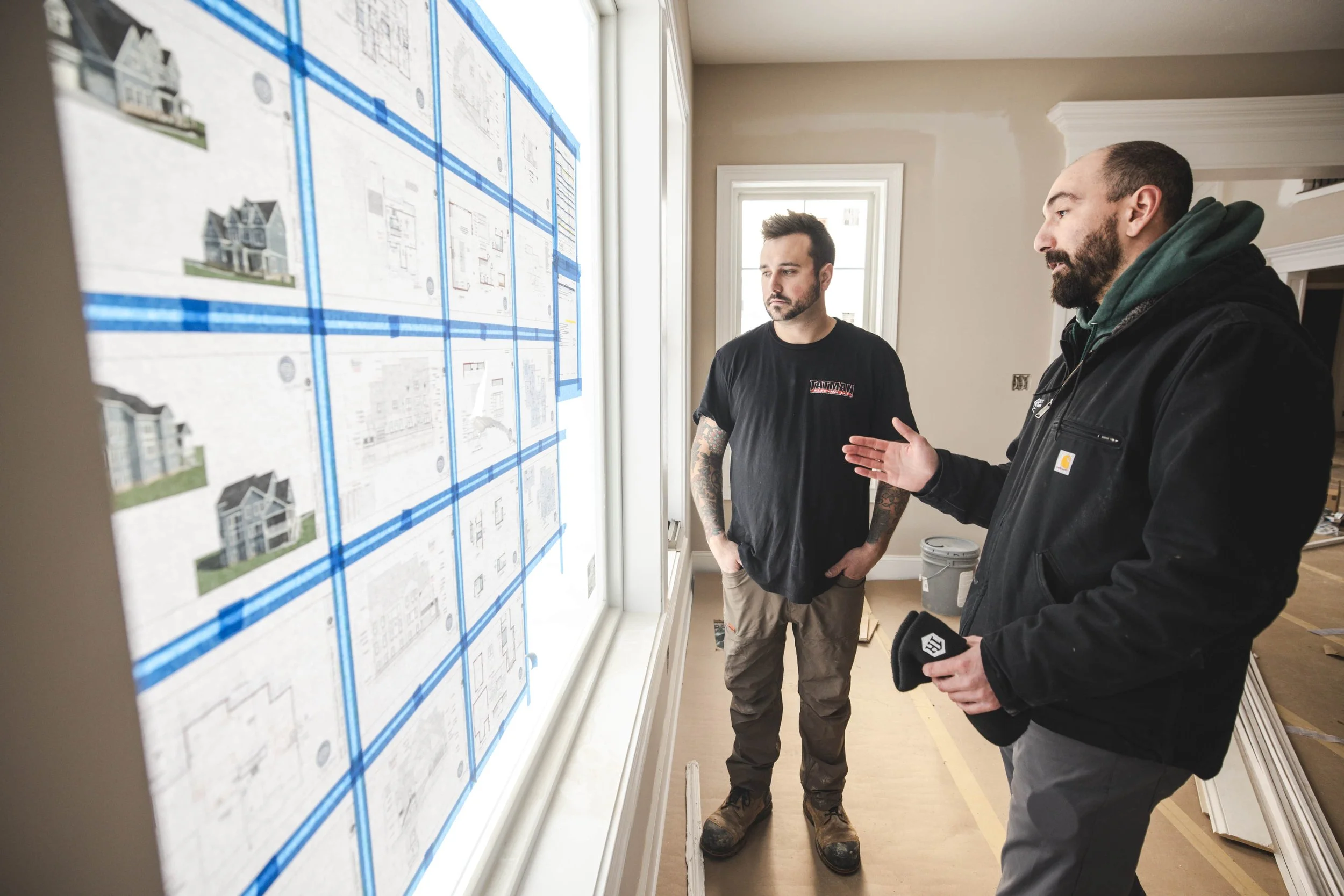 Tatman Electric electricians discussing job progress near large windows in residential new construction Pittsburgh PA