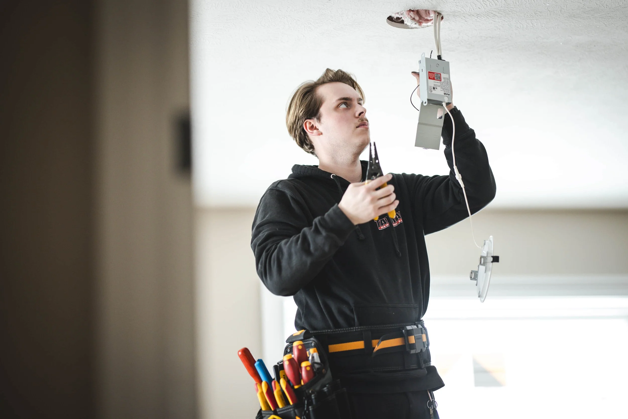 Tatman Electric electrician installing ceiling wiring with tool belt in residential new construction Pittsburgh PA