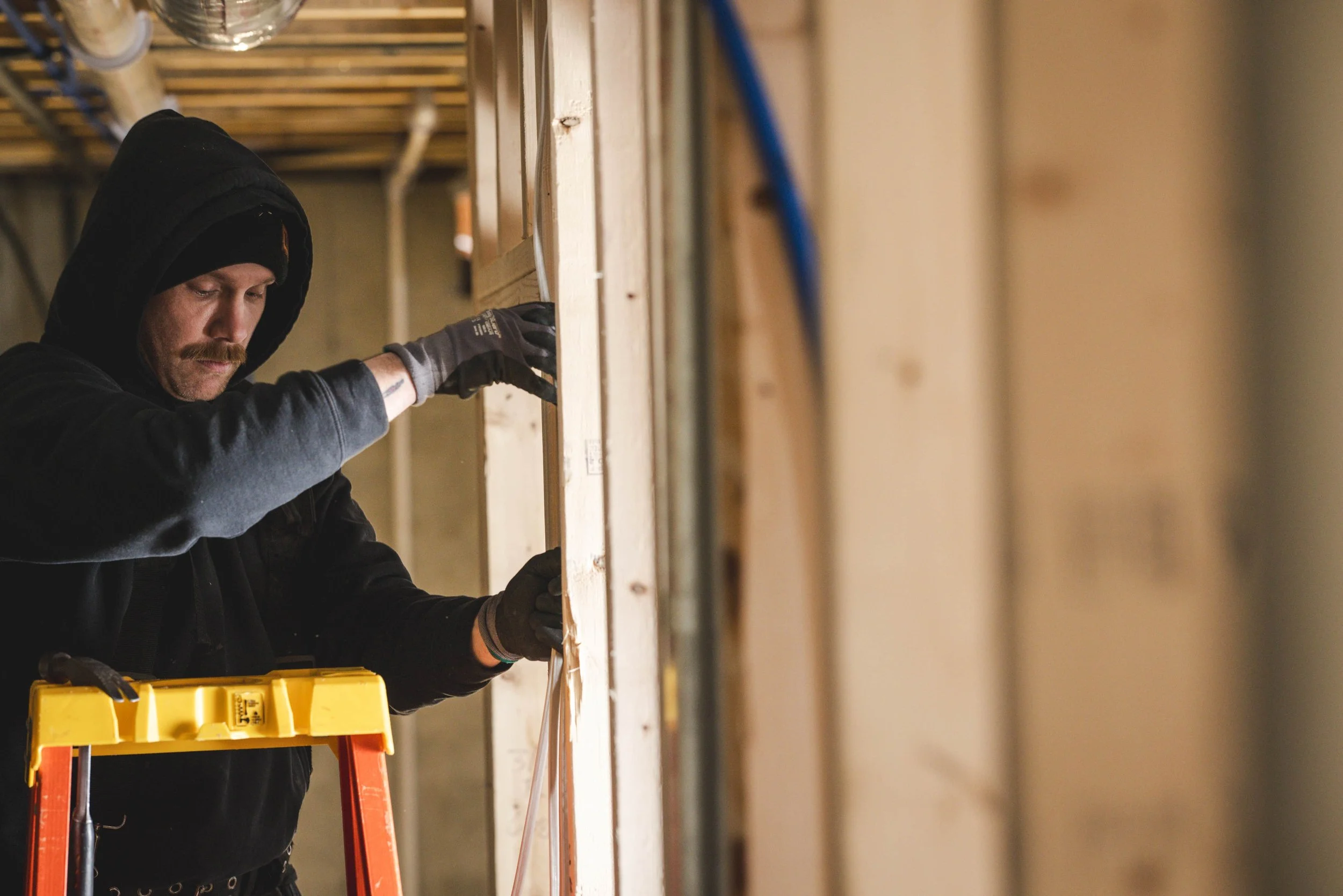 Tatman Electric electrician on ladder running wiring through new construction framing Pittsburgh PA