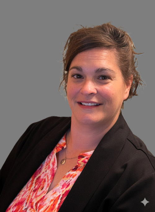 A woman with shoulder-length dark brown hair and a big smile wearing a dark gray turtleneck sweater against a gray background.