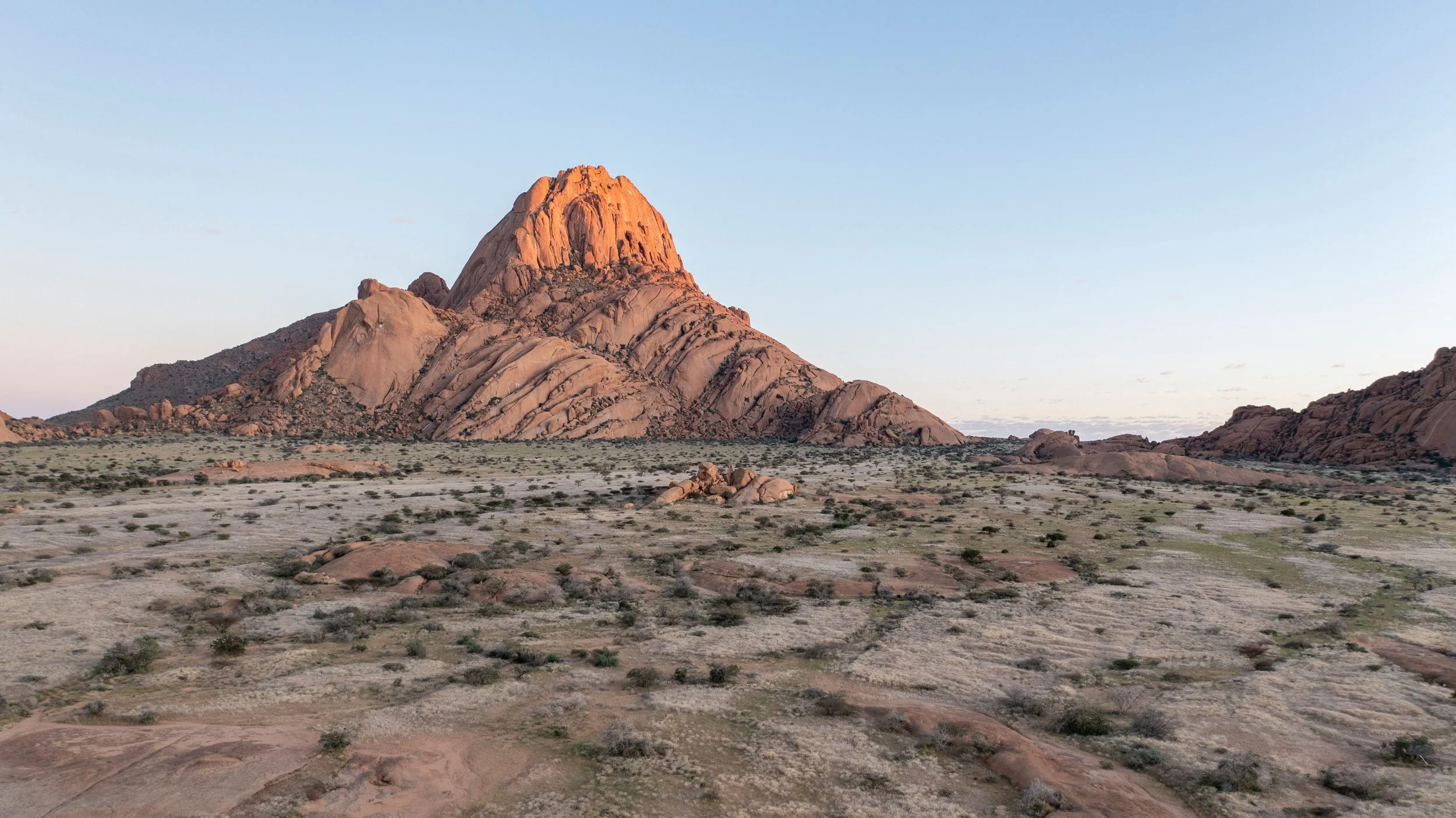 Wüstenlandschaft mit großen Felsen und einer markanten Bergformation bei Sonnenuntergang. Spitzkoppe Namibia. Wo muss man in Namibia hin
