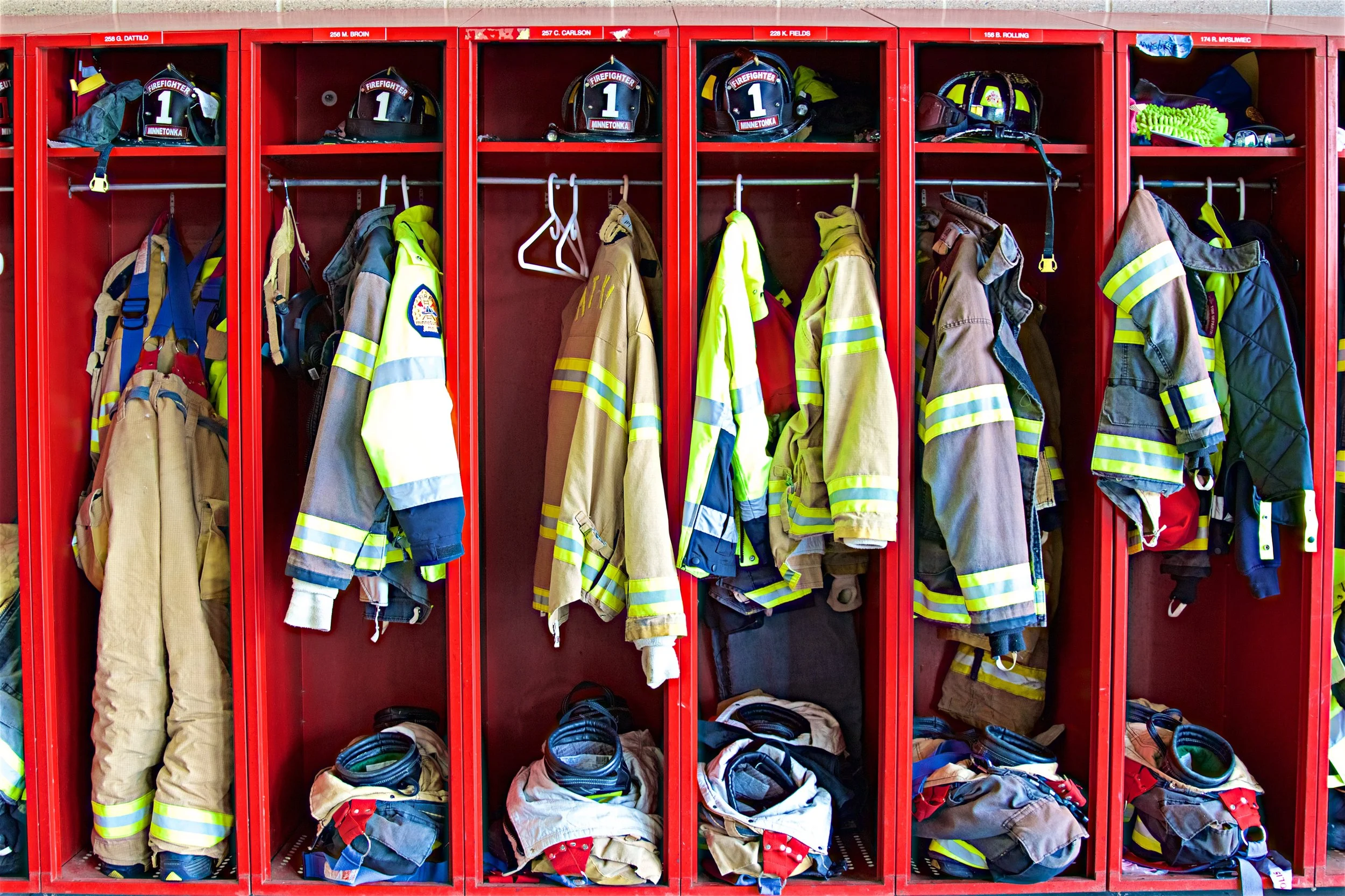 Firefighter lockers with helmets, jackets, pants, and gear.
