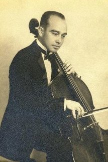 A man in formal attire playing a cello with a bow.