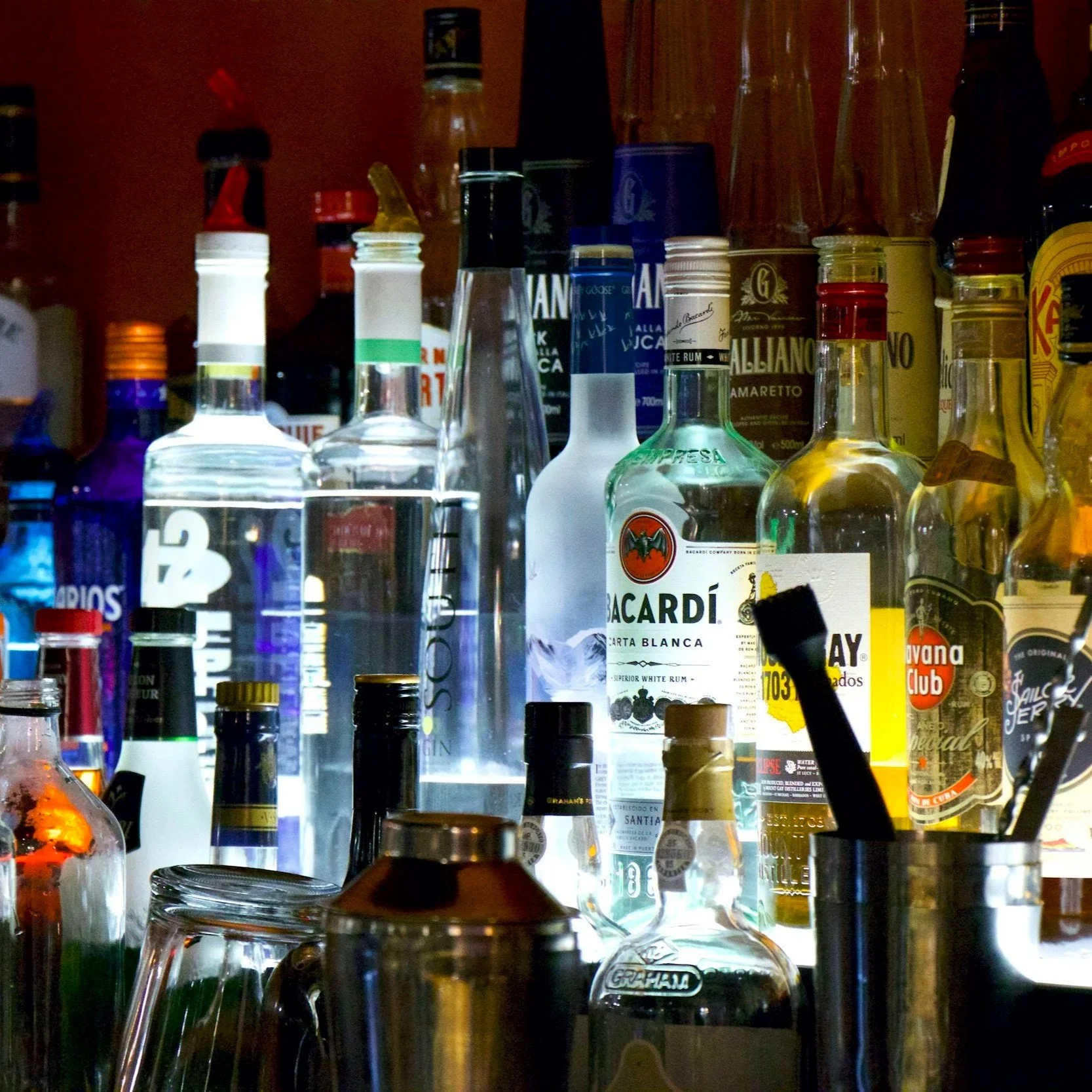 A collection of various liquor bottles on shelves, including Bacardi, Campari, and others.