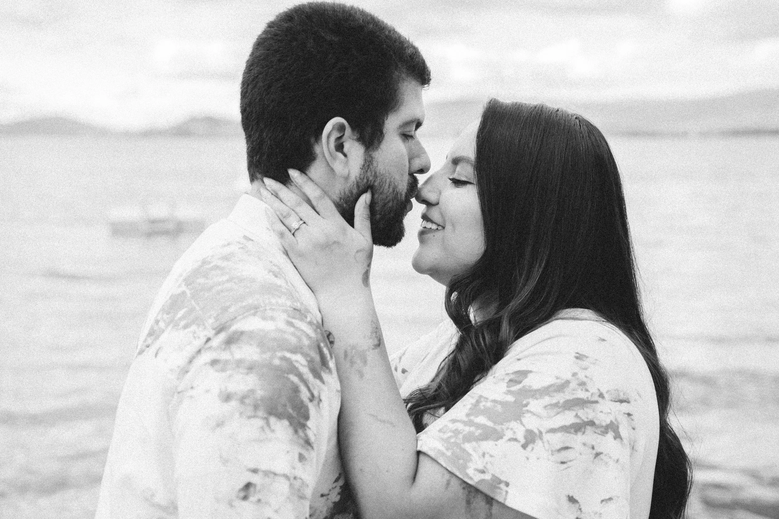 A couple kissing on the beach in black and white.