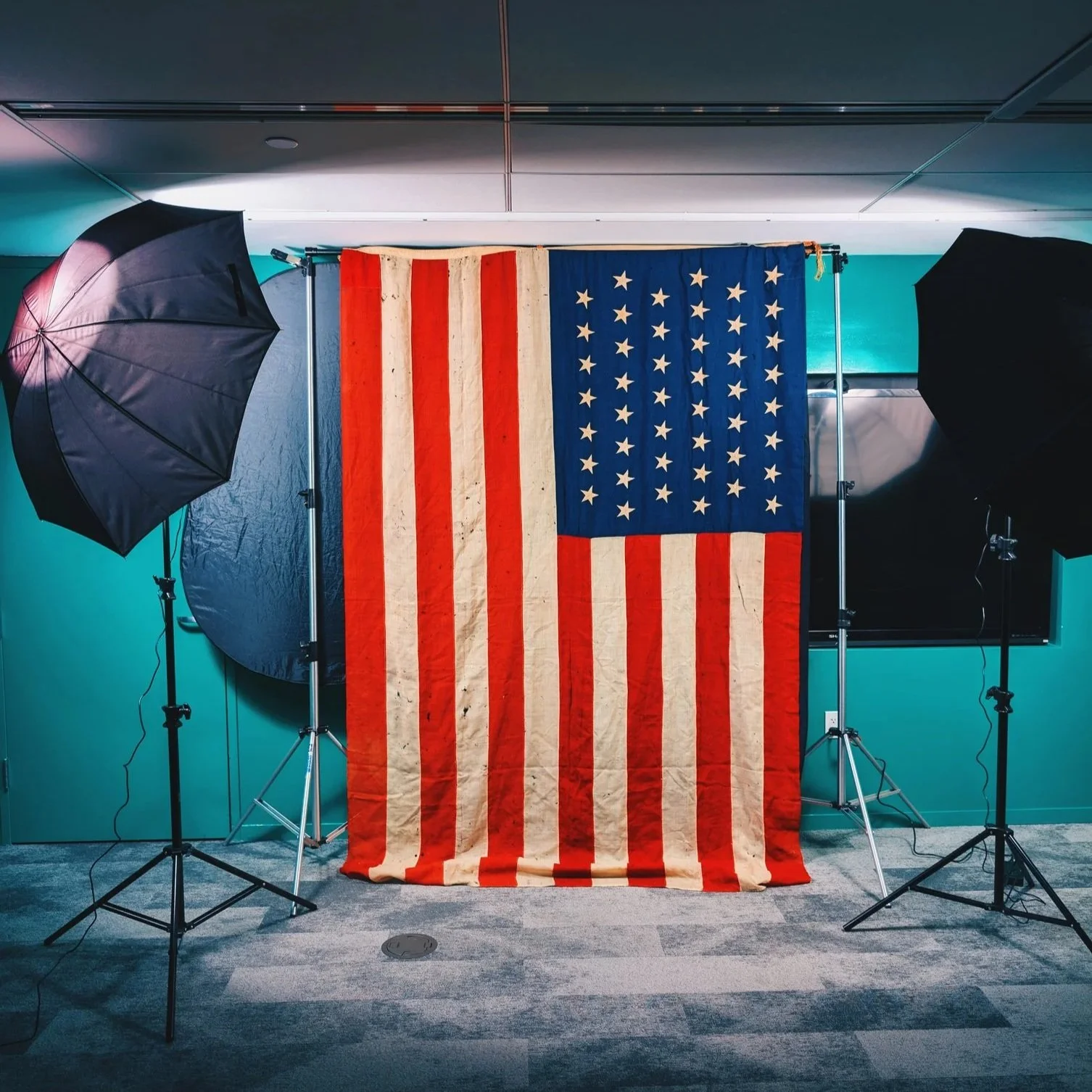 American flag hanging on a backdrop with studio lighting and equipment.