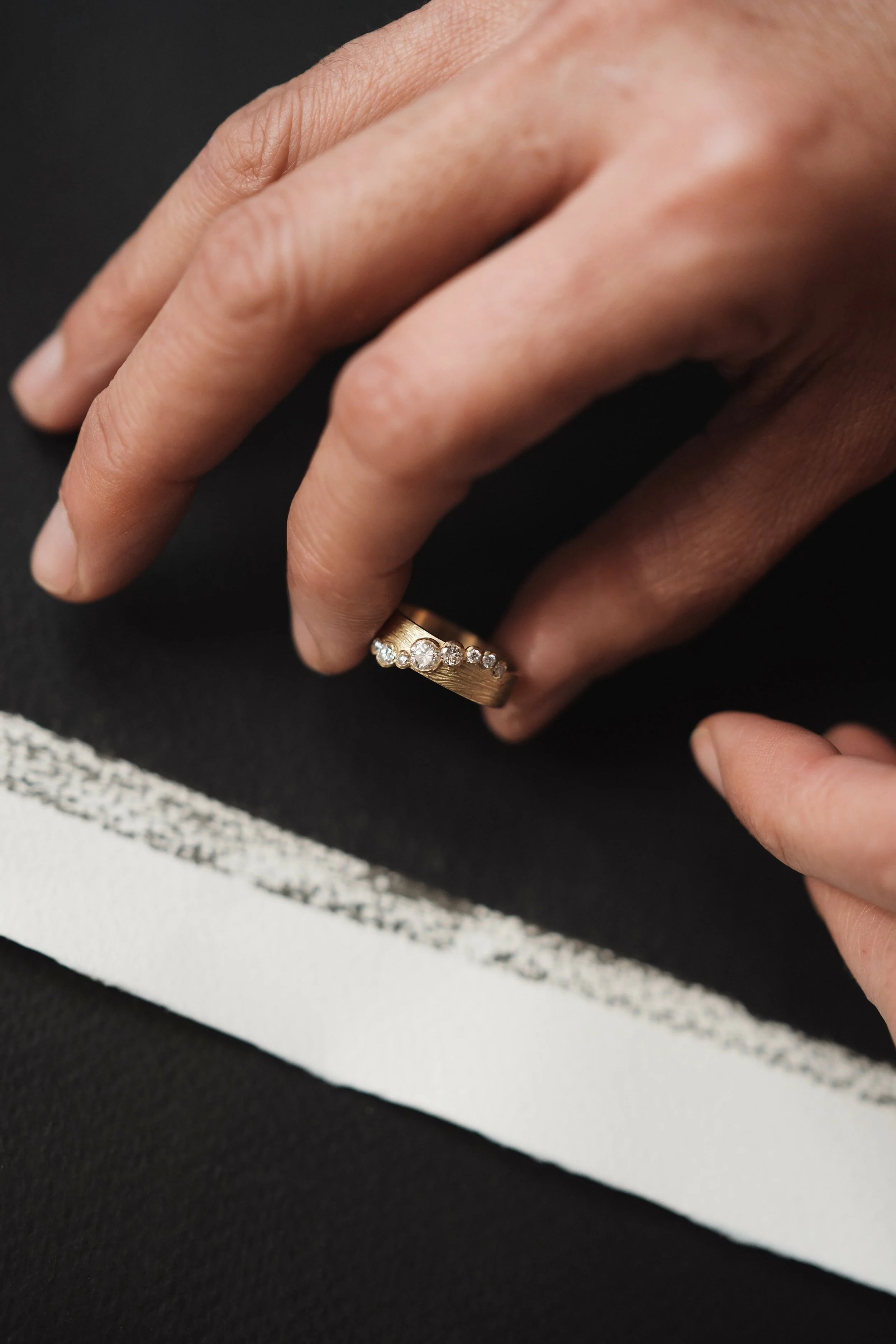Main portant une bague en or avec des diamants.