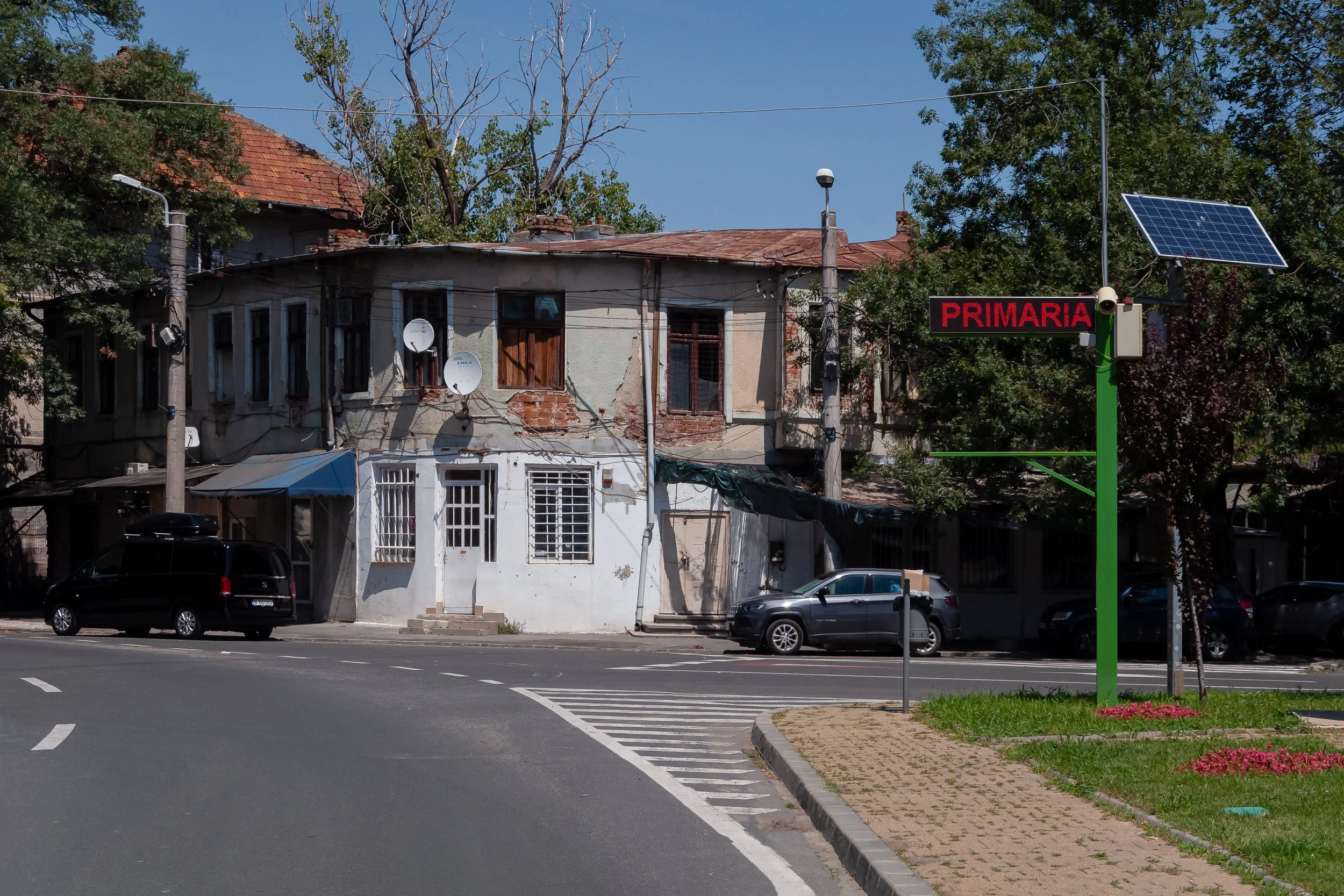 Old house next to a state-funded green patch with a solar panel powered display