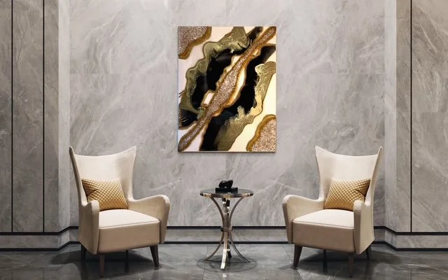 A modern interior with two cream-colored armchairs, a small round glass table, and an abstract artwork on a gray wall.