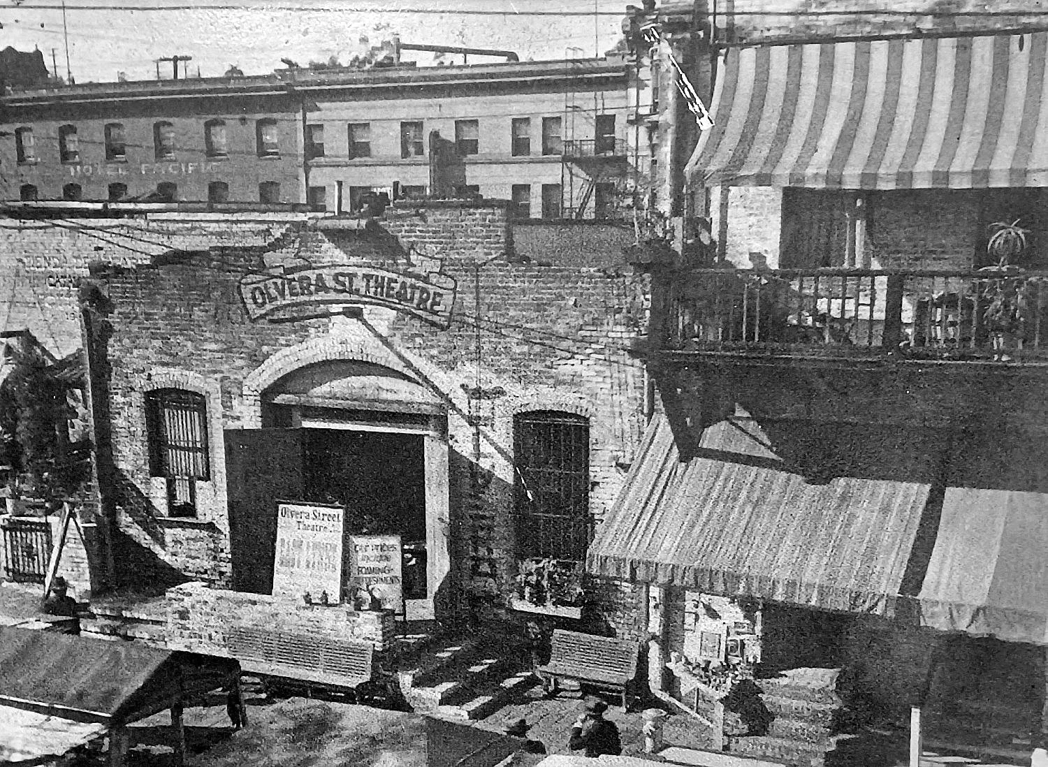 Black and white photo of the Oliver Street Theatre with a sign and some posters in front.